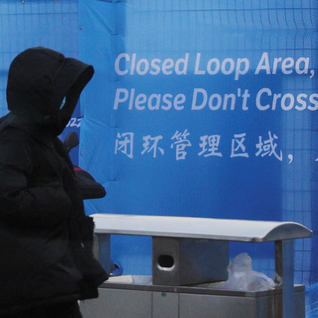  pedestrian passes a sign marking the barrier of the "Closed Loop," a precaution against the coronavirus disease (COVID-19) ahead of the Beijing 2022 Winter Olympics in Beijing, China, January 30, 2022.