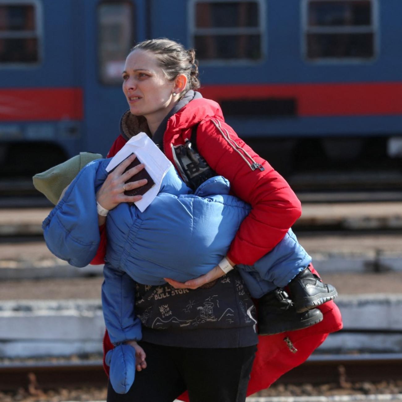 A woman fleeing Russia's invasion of Ukraine carries a child at the train station in Zahony, Hungary March 6, 2022. 