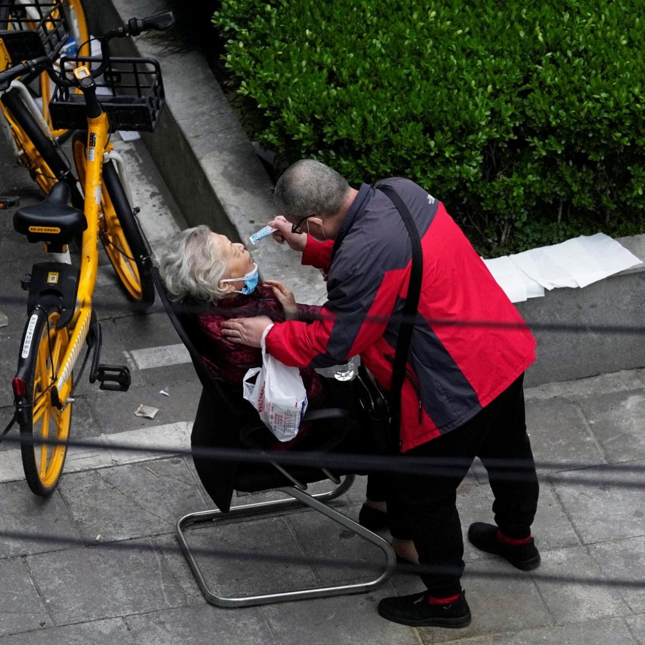 a man helps a woman consume a packet of traditional chinese medicine