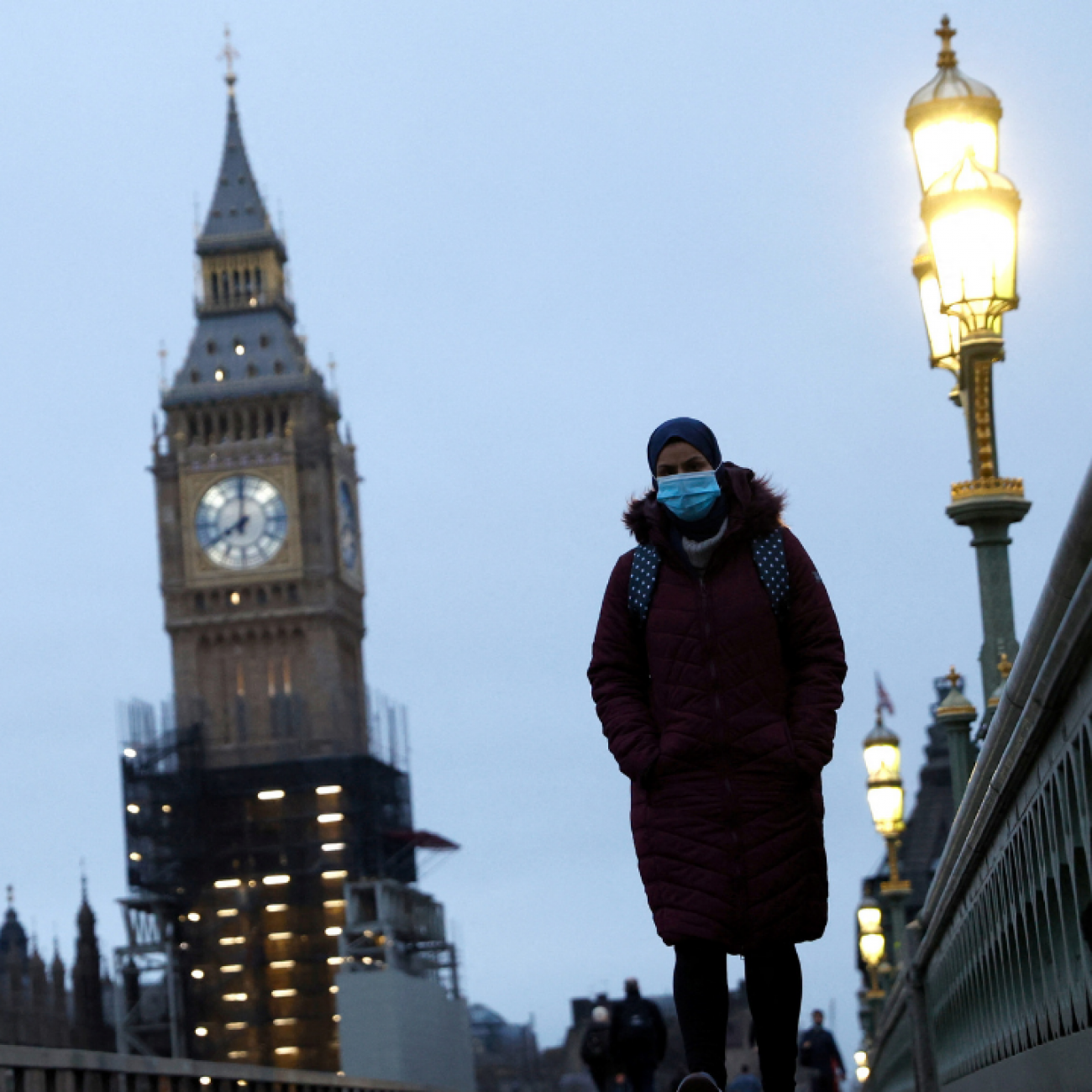 A masked pedestrian walks over Westminster Bridge in London, on January 27, 2022. 