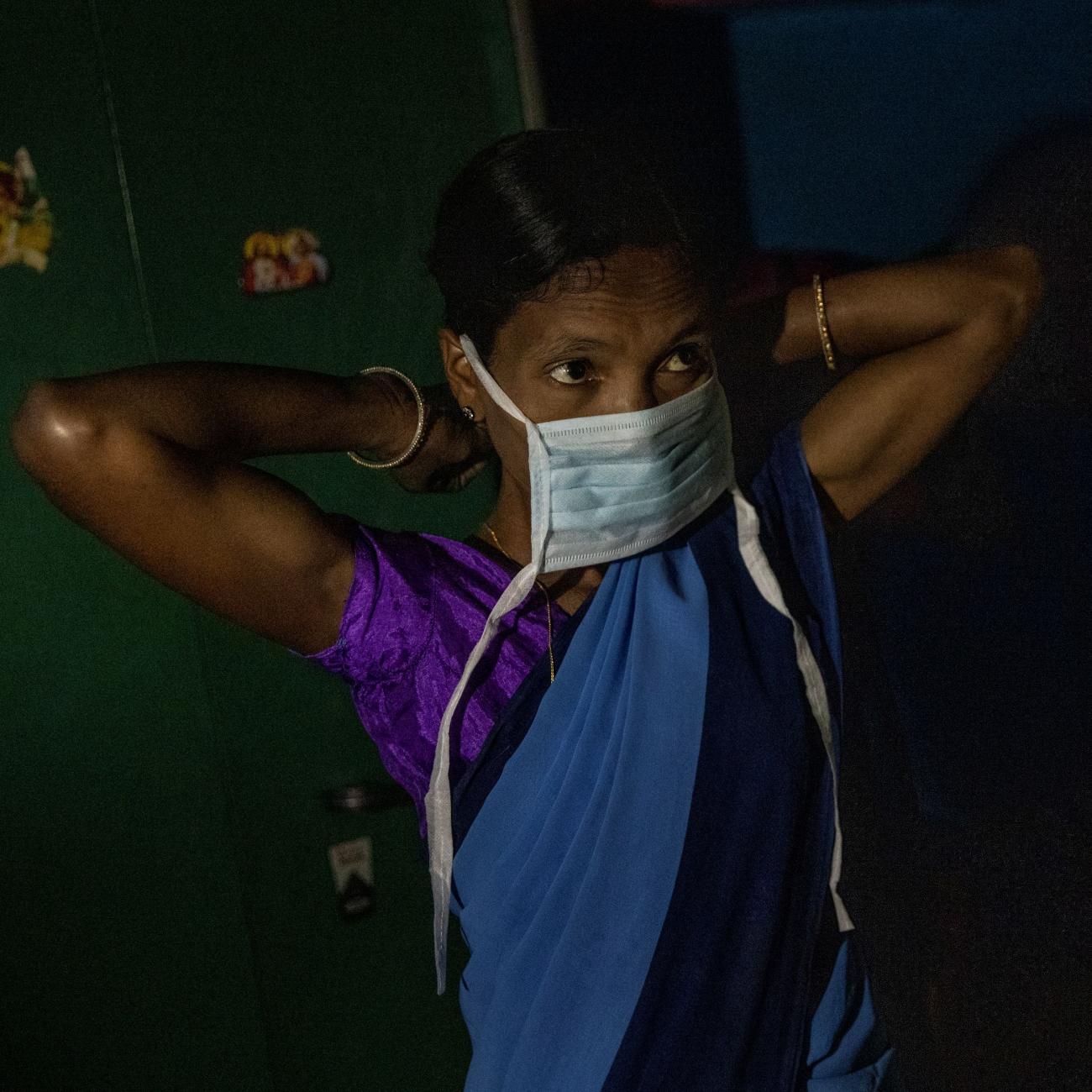  a health worker, puts on a protective face mask as she gets ready to travel