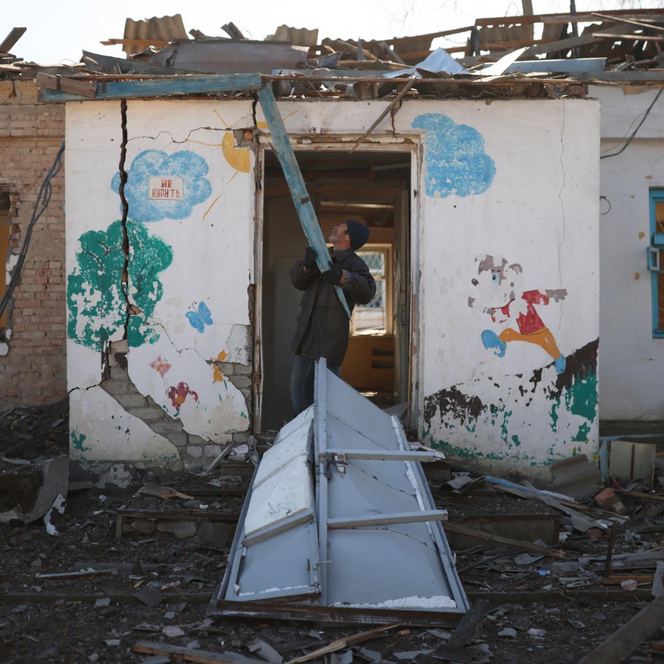 A man clears rubble from a psychiatric hospital that was destroyed by Russian forces