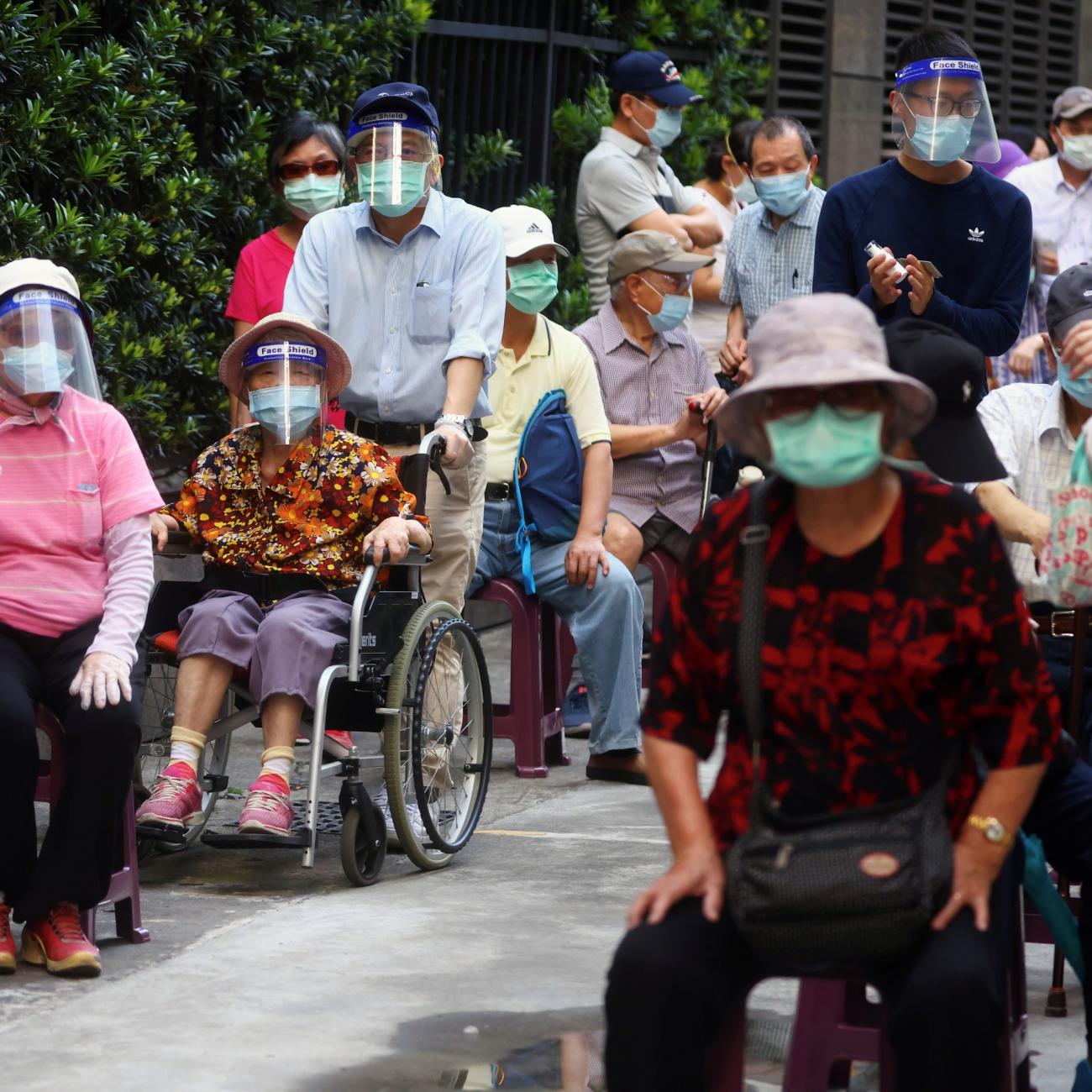 Older people in wheelchairs and blue masks line up to receive the vaccine against the COVID-19 during a vaccination session for elderly people over 85 years old, at a church in Taipei, Taiwan on June 15, 2021.