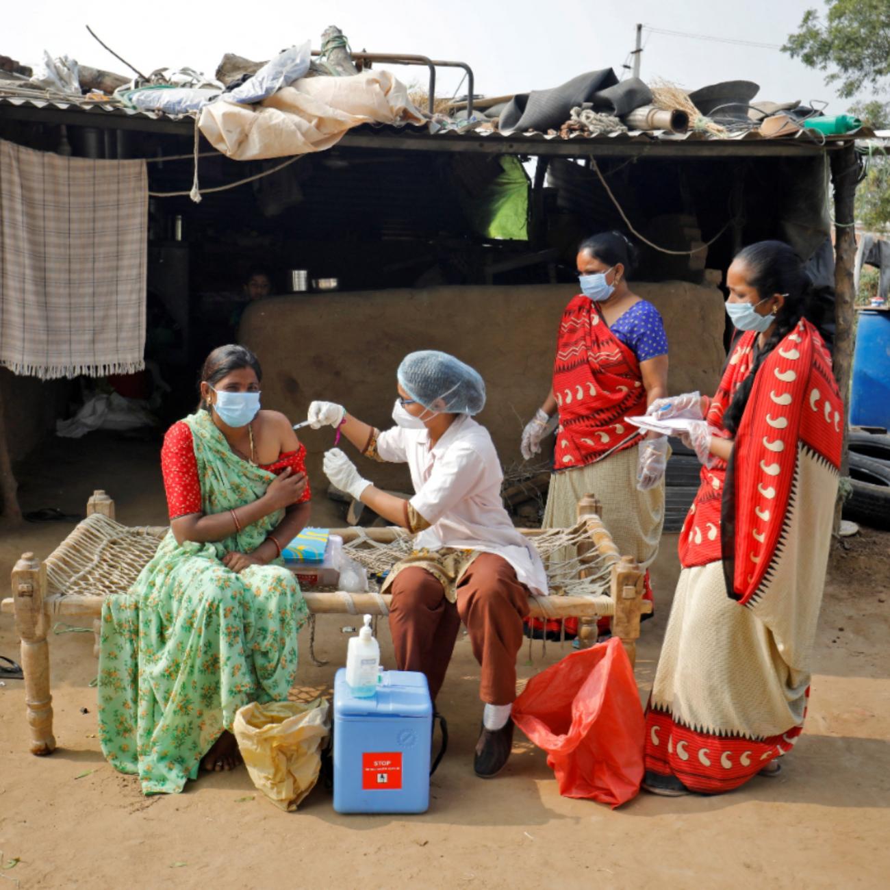 A woman in a green sari receives a dose of a COVID-19 vaccine manufactured by Serum Institute of India, outside her house during a door-to-door vaccination drive on the outskirts of Ahmedabad, India, on December 15, 2021. 