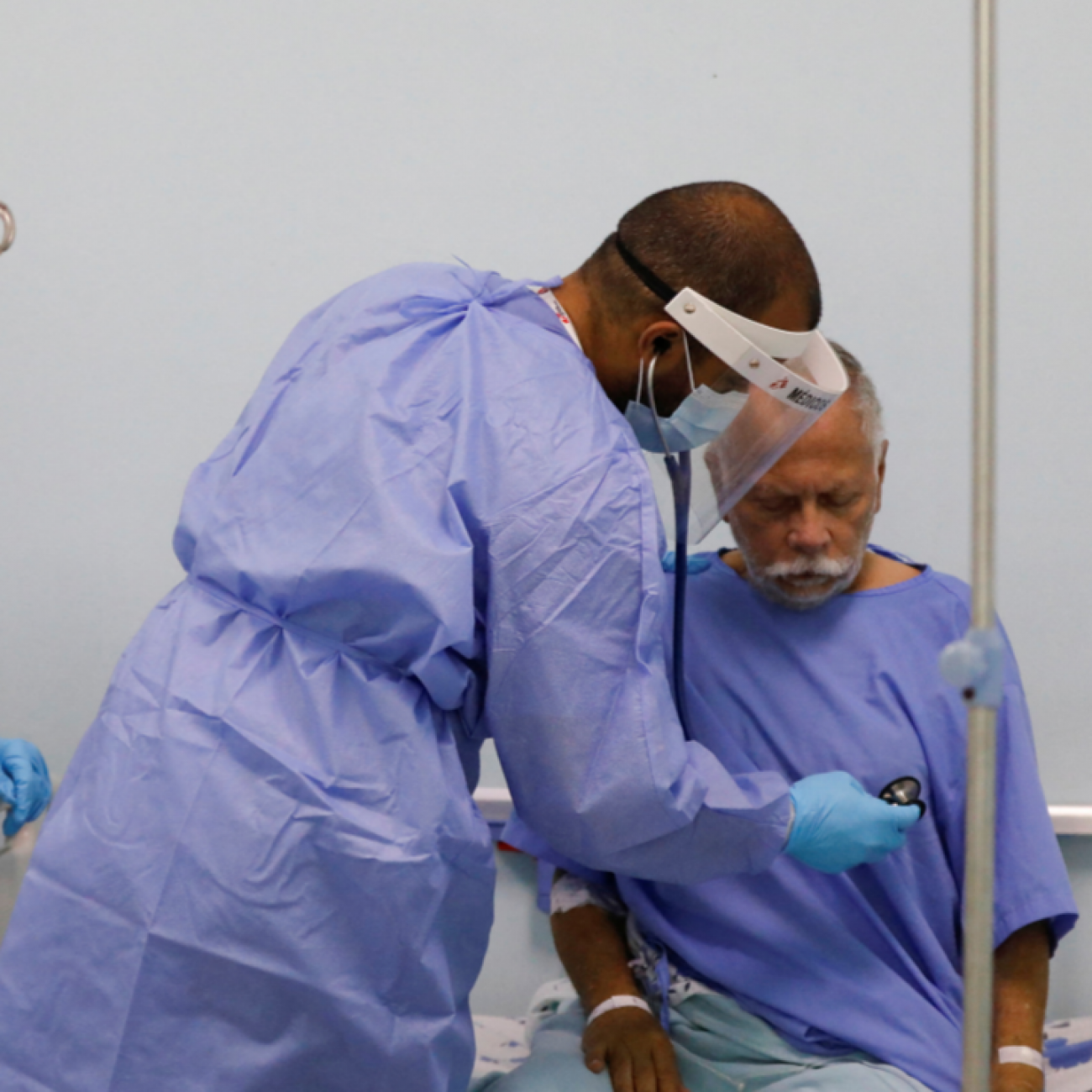 A physician with Doctors Without Borders (MSF) places his stethoscope to the chest of hospital patient Marco Vargas, who has COVID, in Caracas, Venezuela, on February 1, 2022. 