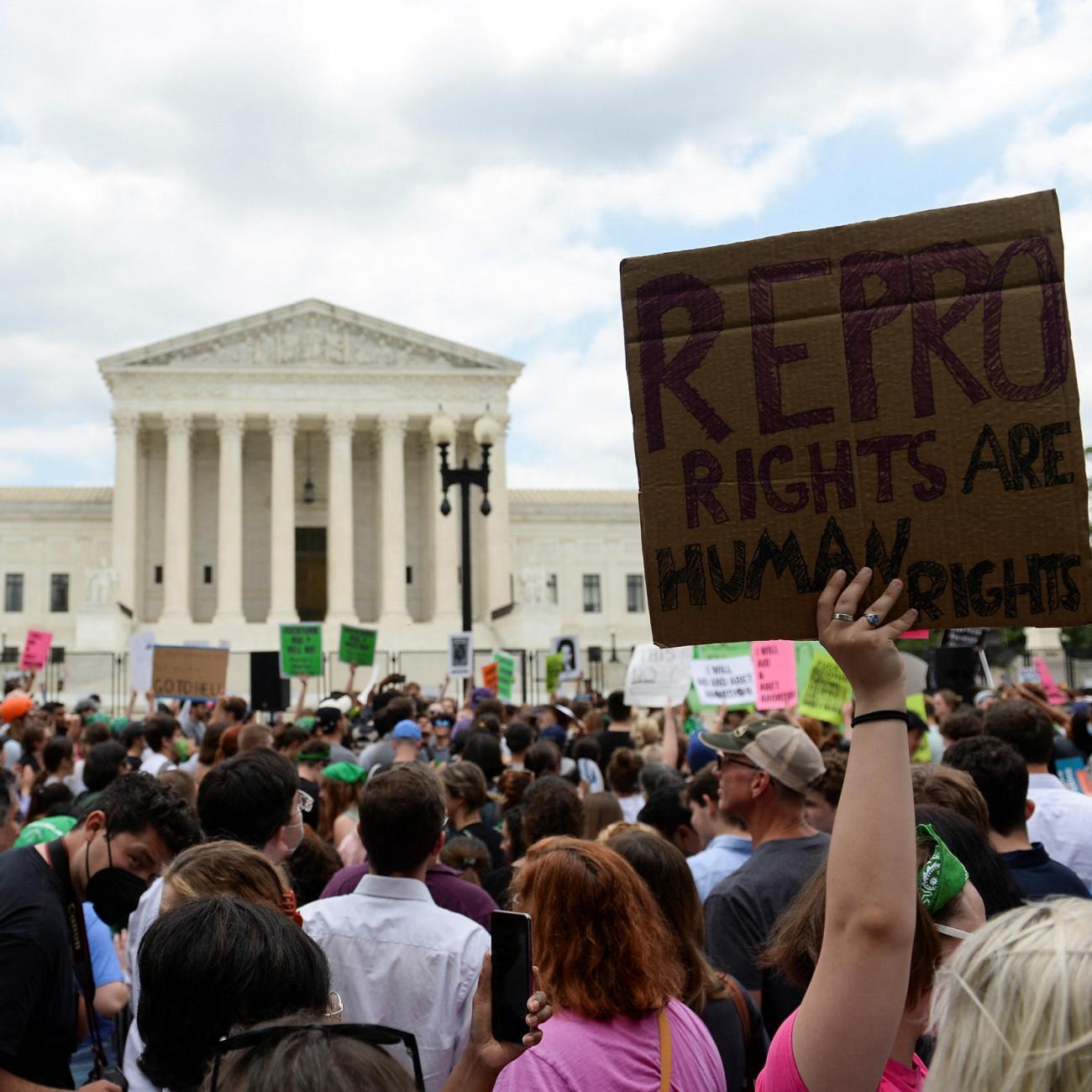 Abortion rights supporters holding pink and green signs face the white columns of the U.S. Supreme Court Building as they demonstrate against the Dobbs v Women's Health Organization ruling in Washington, U.S., June 24, 2022.