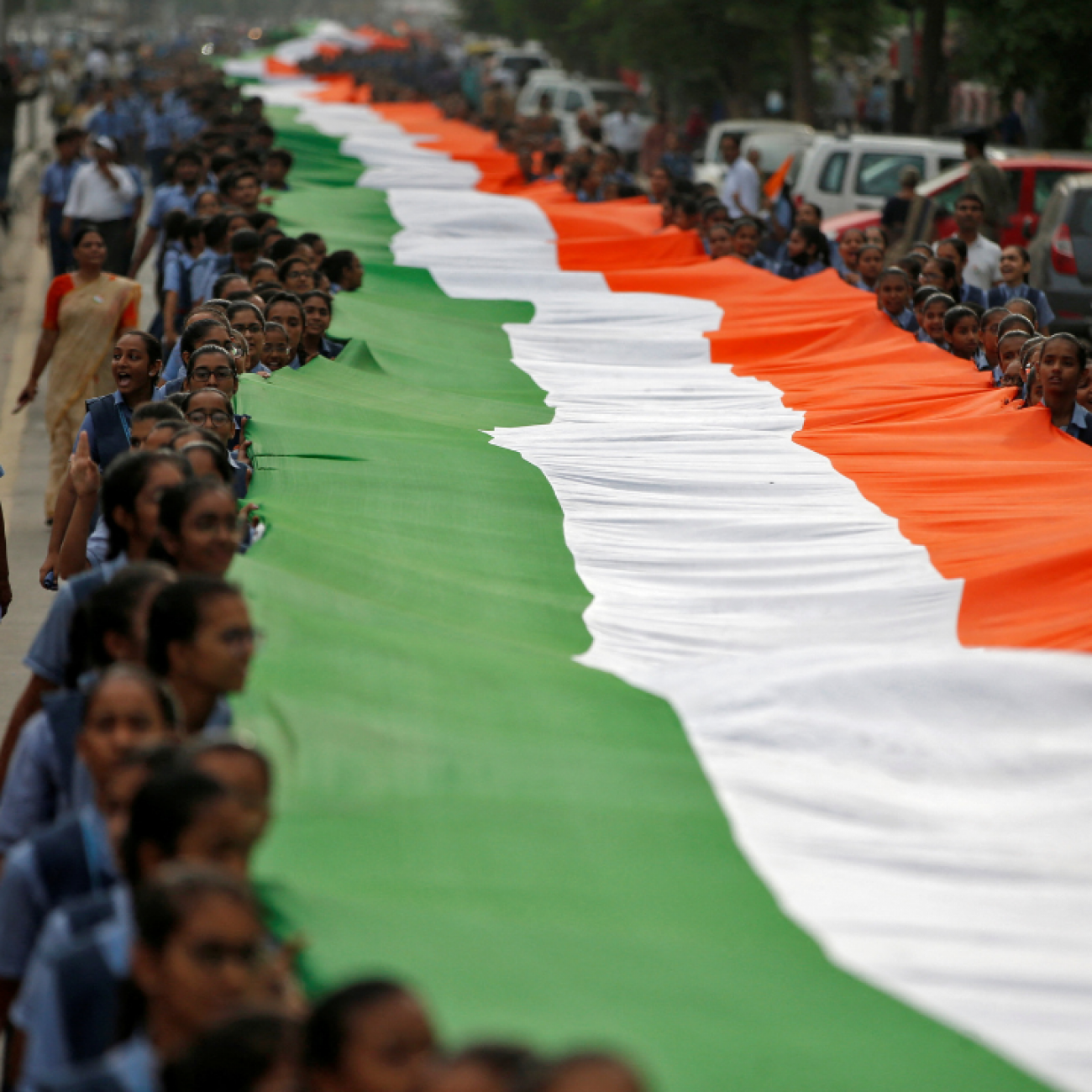 Students hold a giant Indian national flag with green, white and orange stripes, during celebrations commemorating 75 years of India's Independence, in Ahmedabad, India, August 8, 2022. 