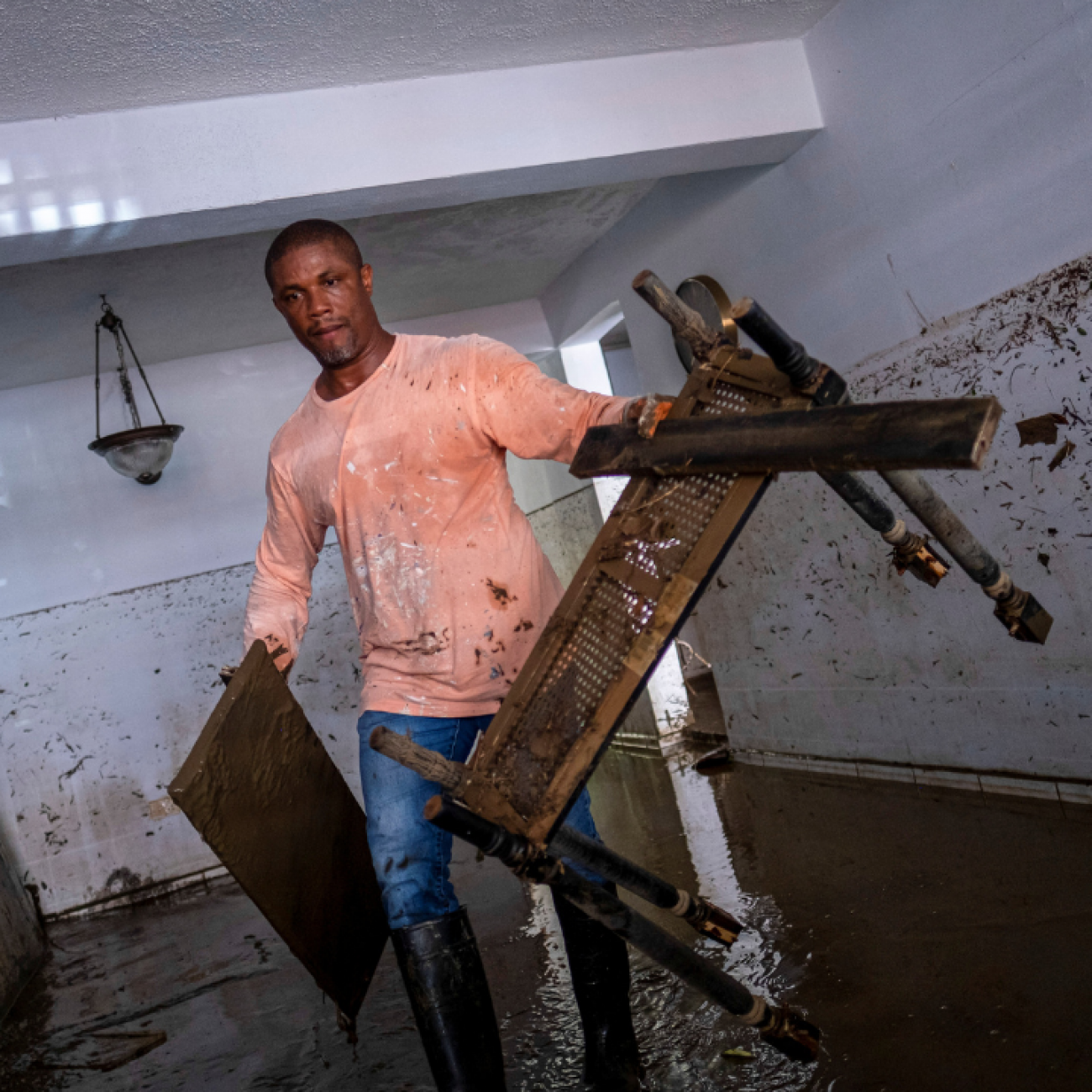 A man wades through knee-deep water in his home, carrying damaged furniture in the aftermath of Hurricane Fiona, in Toa Baja, Puerto Rico, on September 20, 2022. REUTERS/Ricardo Arduengo
