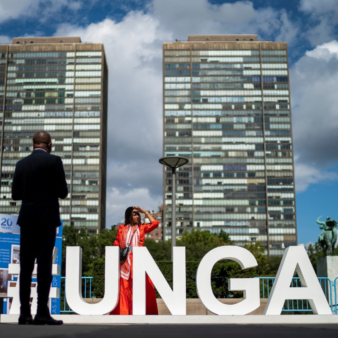 People stand outside the 77th Session of the United Nations General Assembly, where giant white letters UNGA stand on the ground, at UN Headquarters in New York, on September 20, 2022. 