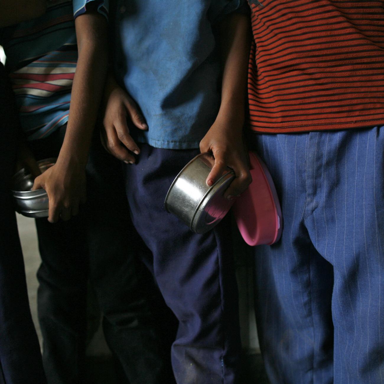 The arms of school boys are seen carrying their tiffin boxes as they wait to receive their free mid-day meal, distributed by a government-run primary school, in New Delhi July 19, 2013. 