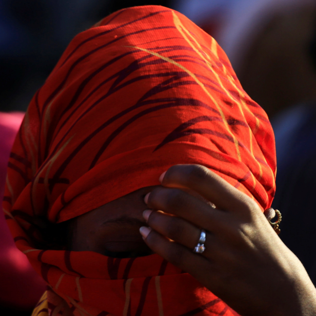 A close-up photo of an Ethiopian woman wearing a read head scarf with her hand held to her forehead. She fled the ongoing fighting in Tigray, in Hamdayet village near the Sudan-Ethiopia border, in Kassala State, Sudan, on November 22, 2020. 