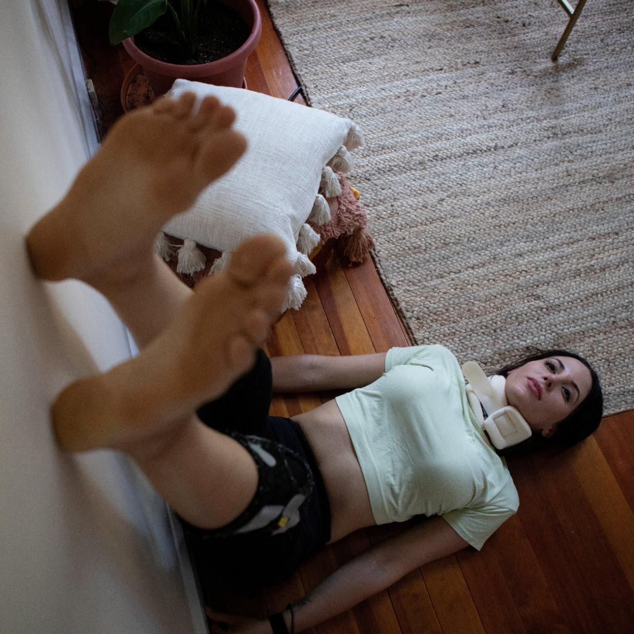 Lauren Nichols, who has long COVID, rests with her feet in the air to get more blood to her head after feeling light-headed in her home in Andover, Massachusetts, on August 3, 2022.