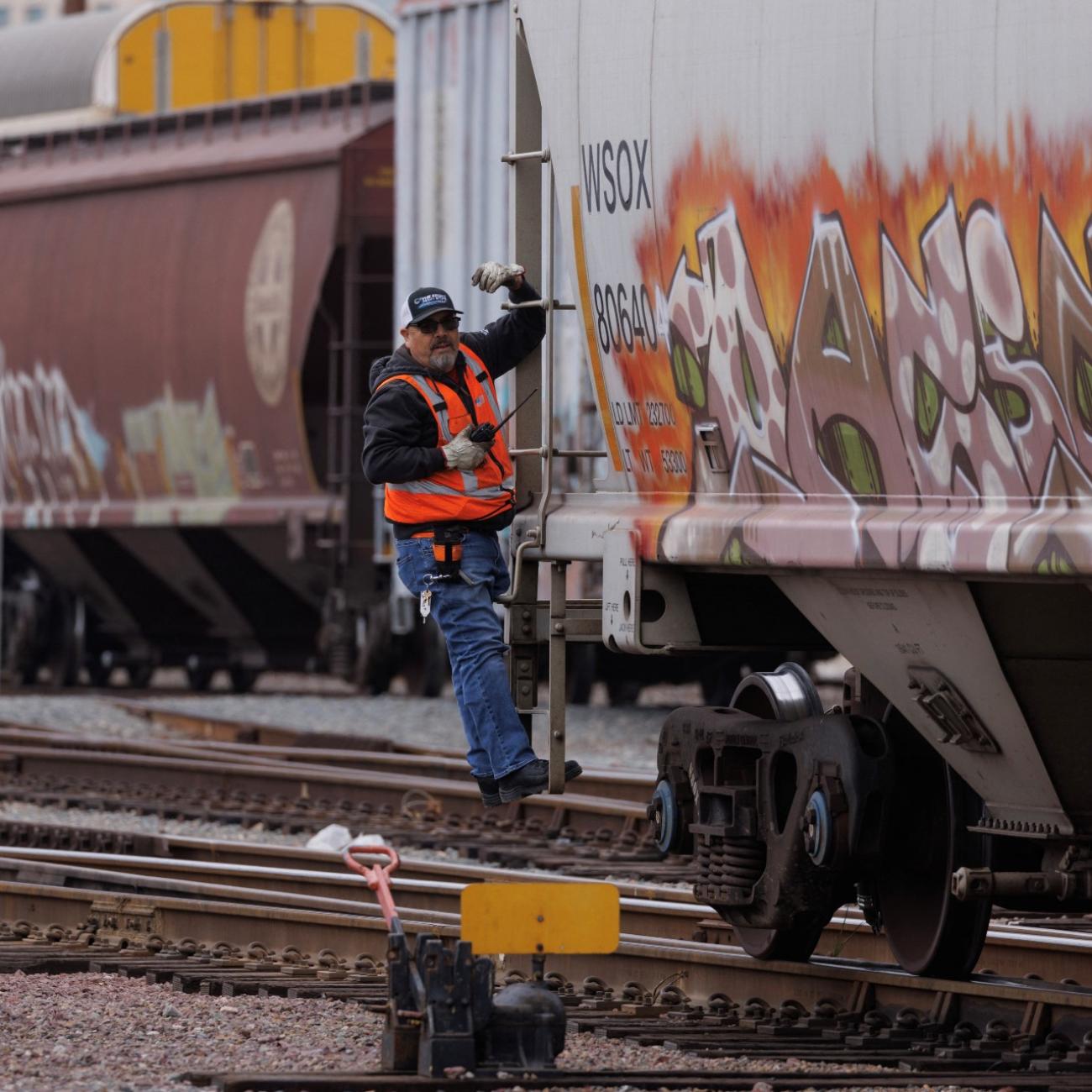 A railway worker helps load railcars onto a train in San Diego, California, U.S., November 30, 2022.