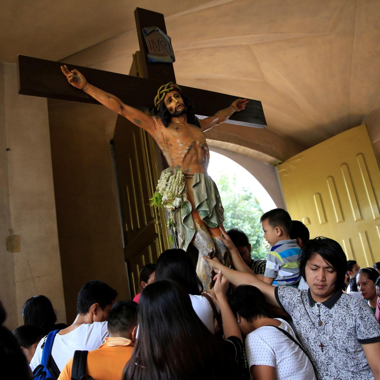 Filipino Catholic devotees touch the statue of crucified Jesus Christ after attending a mass at a National Shrine of Our Mother of Perpetual Help in Baclaran, Paranaque city, metro Manila, Philippines September 18, 2016.