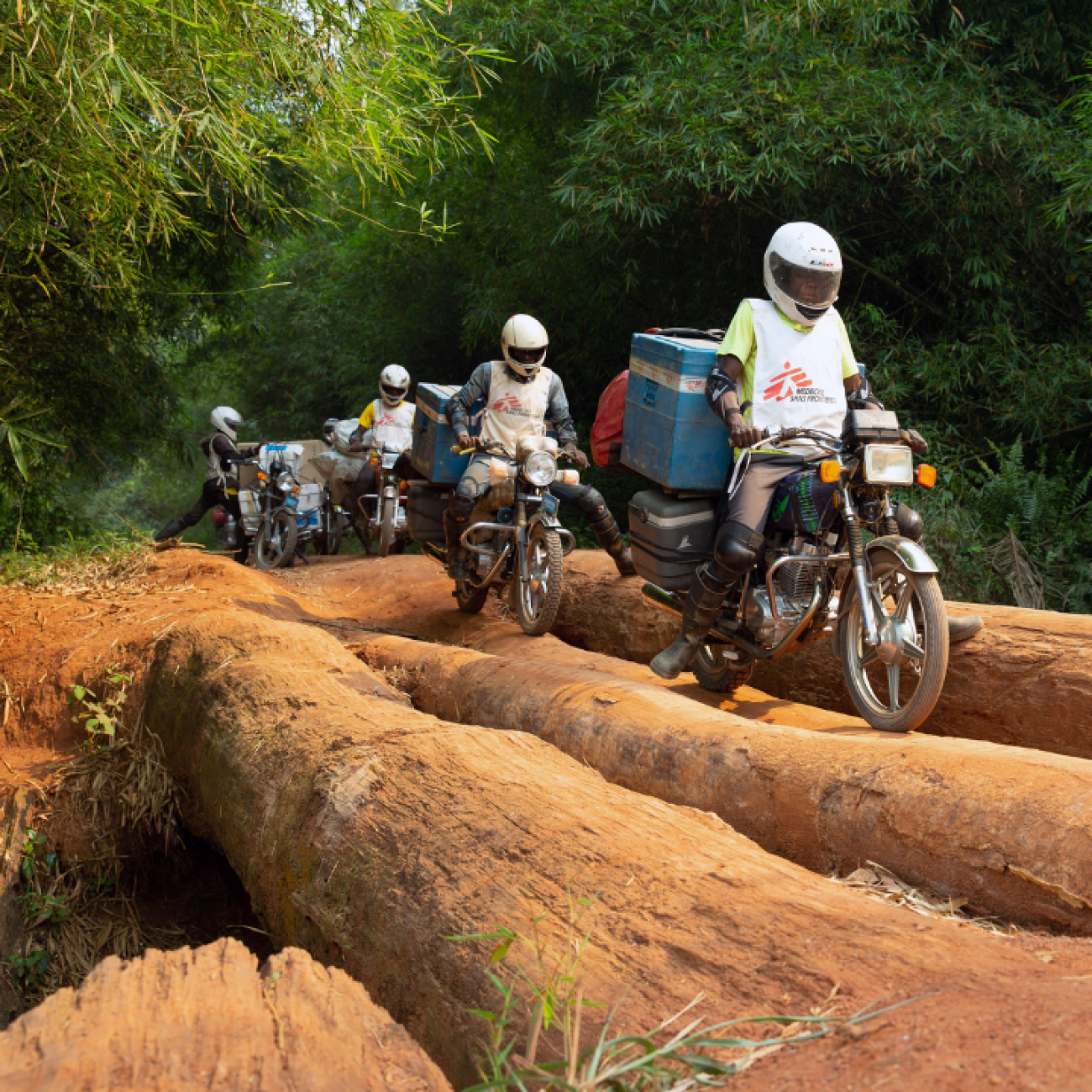 A motorcycle convoy carrying measles vaccines for the NGO Doctors Without Borders crosses a log bridge in Mongala Province, in the Democratic Republic of Congo, on February 27, 2020. 