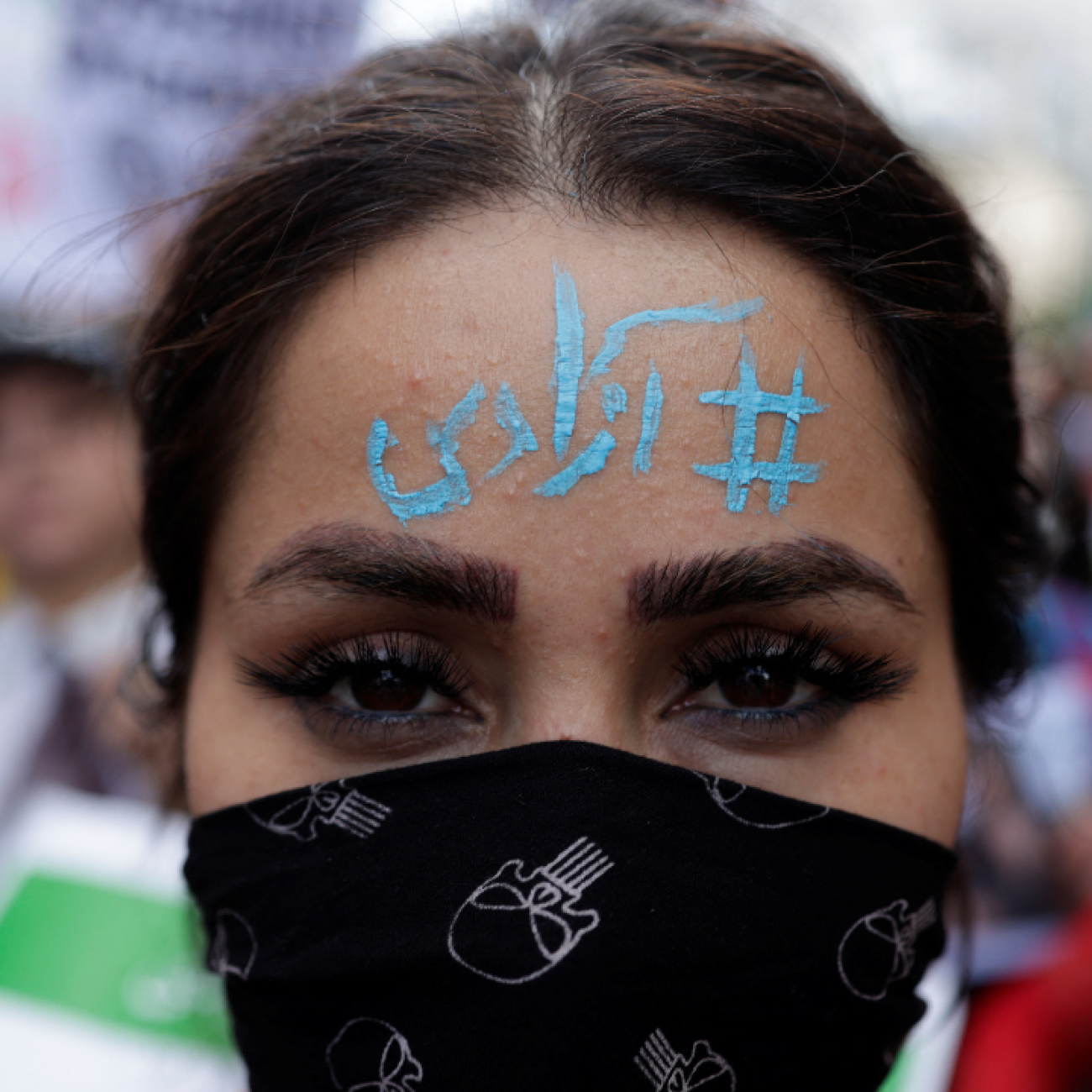 A woman wears a face mask and has the words "Freedom" written in blue paint on her forehead in Arabic. She takes part in a protest following the death of Mahsa Amini, near the Iranian consulate in Istanbul, Turkey, October 4, 2022. 