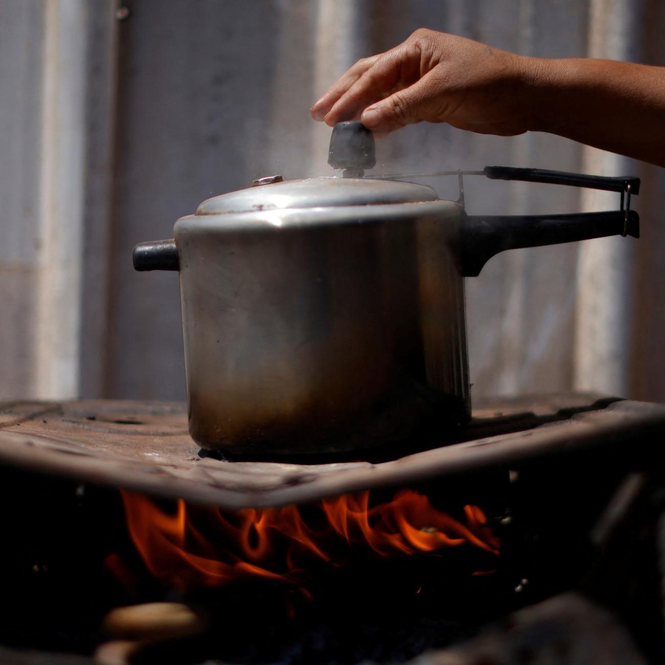 Luciana Messias dos Santos, 29, cooks using firewood outside her home in the Estrutural favela in Brasilia, Brazil, August 31, 2022. 