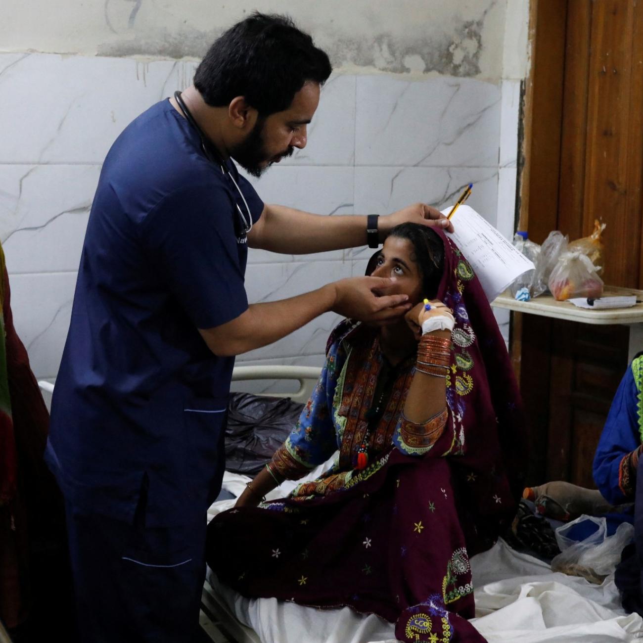 Naveed Ahmed, a doctor, gives medical assistance to Hameeda, who is suffering from malaria, at Sayed Abdullah Shah Institute of Medical Sciences in Sehwan, Pakistan, on September 29, 2022.