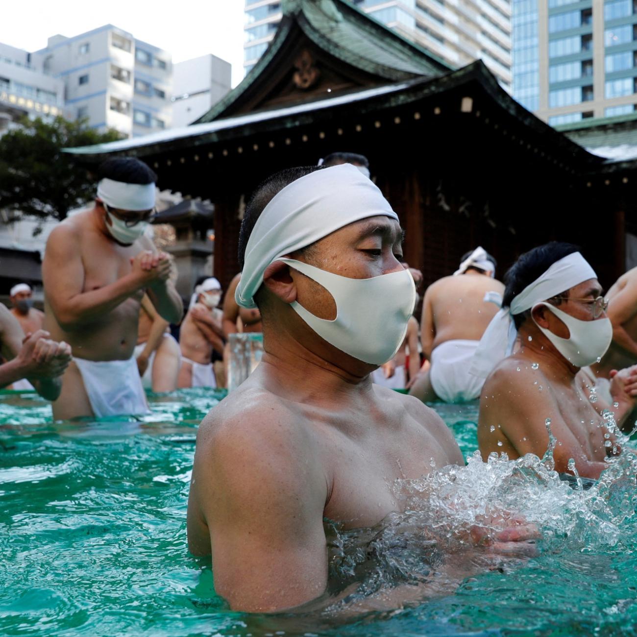 Participants wearing protective face masks amid the coronavirus disease (COVID-19) outbreak, pray as they take an ice-cold bath during a ceremony to purify their souls and to wish for overcoming the pandemic at the Teppozu Inari shrine in Tokyo, Japan, January 9, 2022.