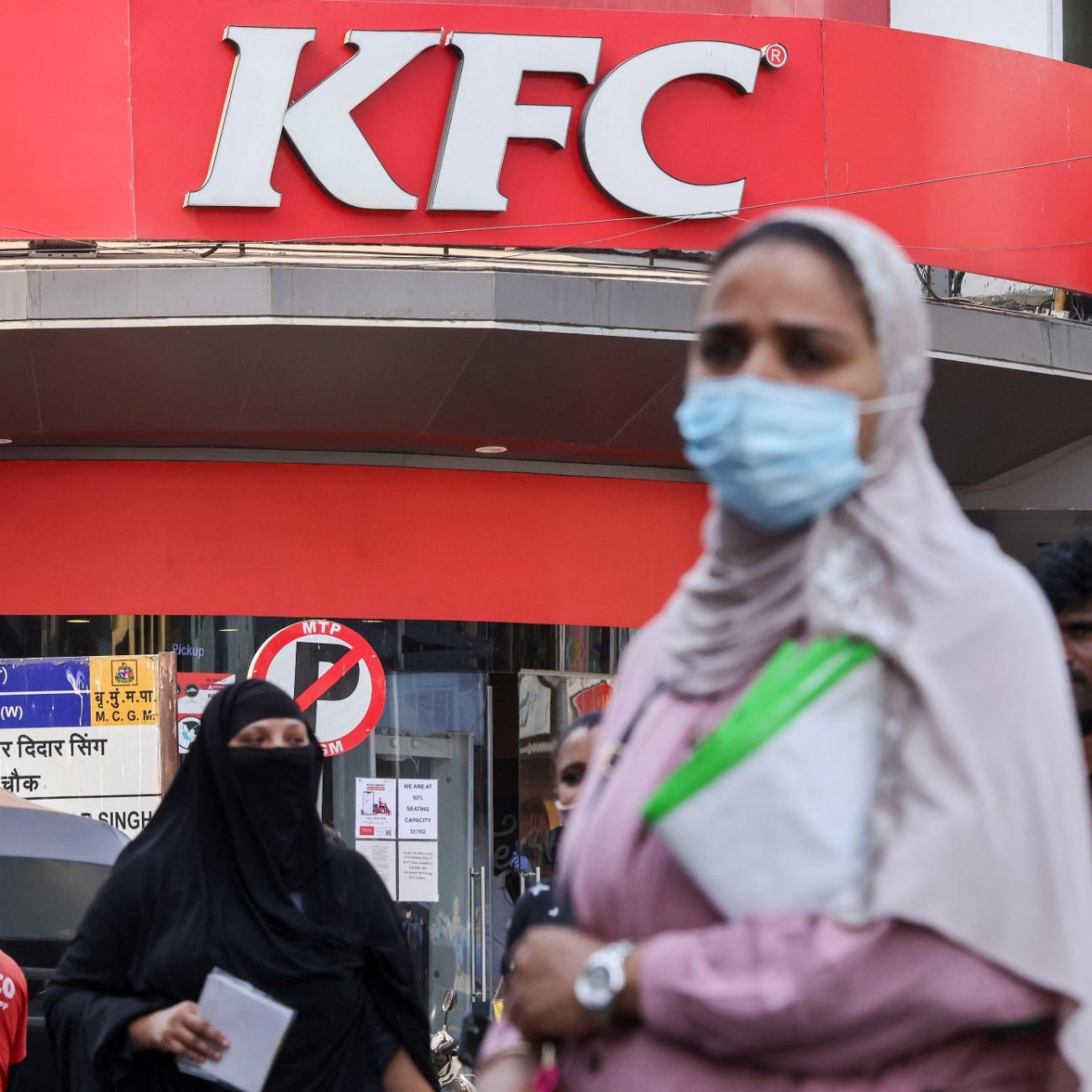 a woman stands in front of a kfc