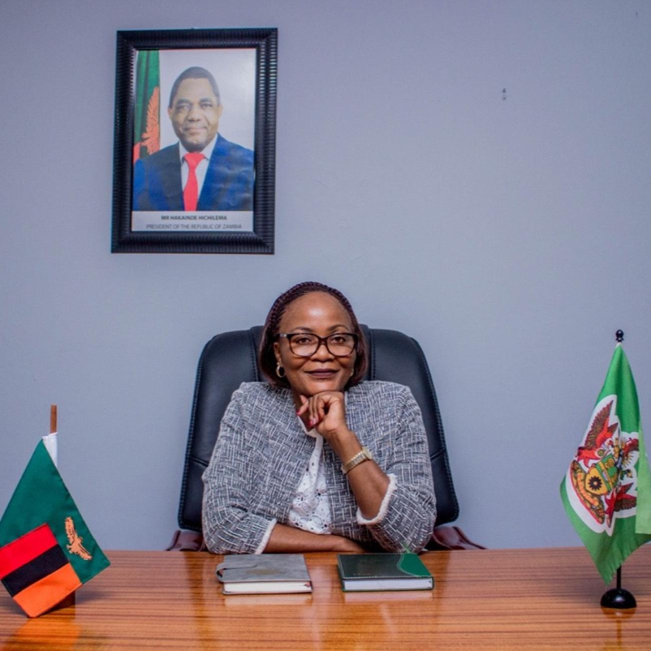 Mayor Chilando Chitangala wears a light blue tweed blazer and sitesin a black desk chair in her office