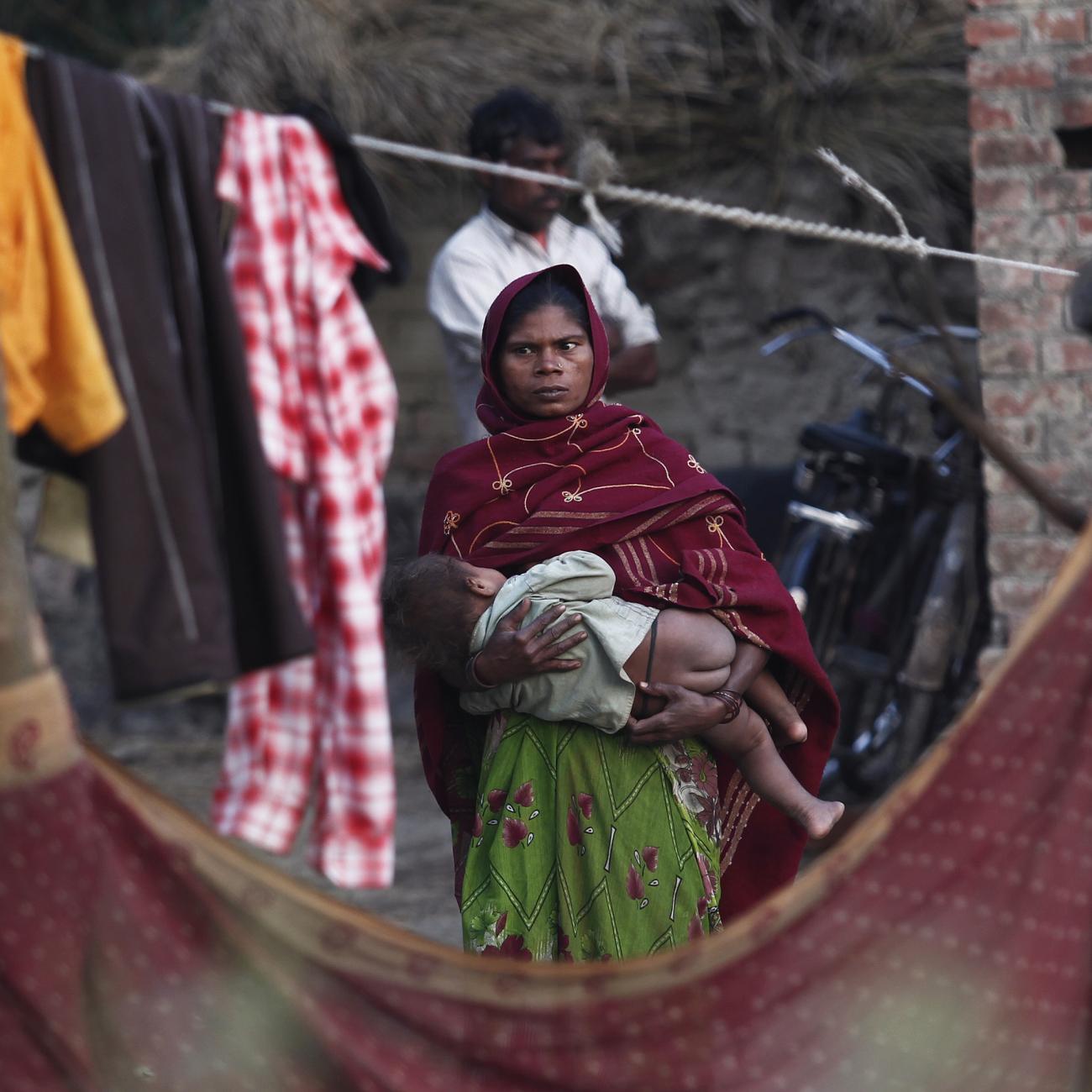 A woman holds her child as she stands outside her house at Dalit village of Bhaddi Kheda in the northern Indian state of Uttar Pradesh January 15, 2012.