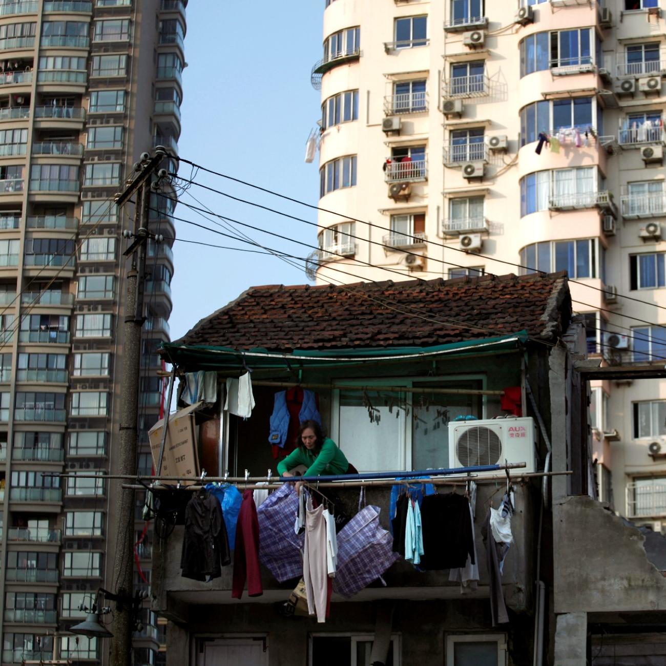 A woman stands at the balcony of her house which will be demolished to build new apartments in downtown Shanghai, China, on December 1, 2010. 