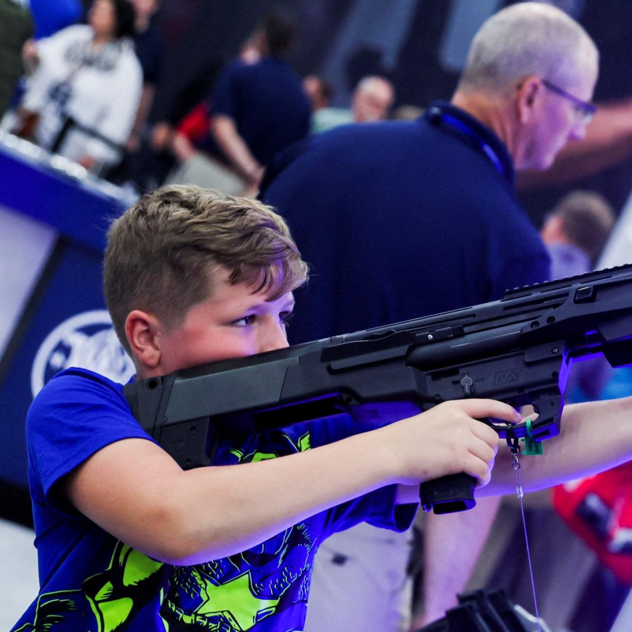 A boy tries out a 12 gauge Smith and Wesson shotgun as people attend the National Rifle Association (NRA) annual convention, in Houston, Texas, on May 28, 2022.