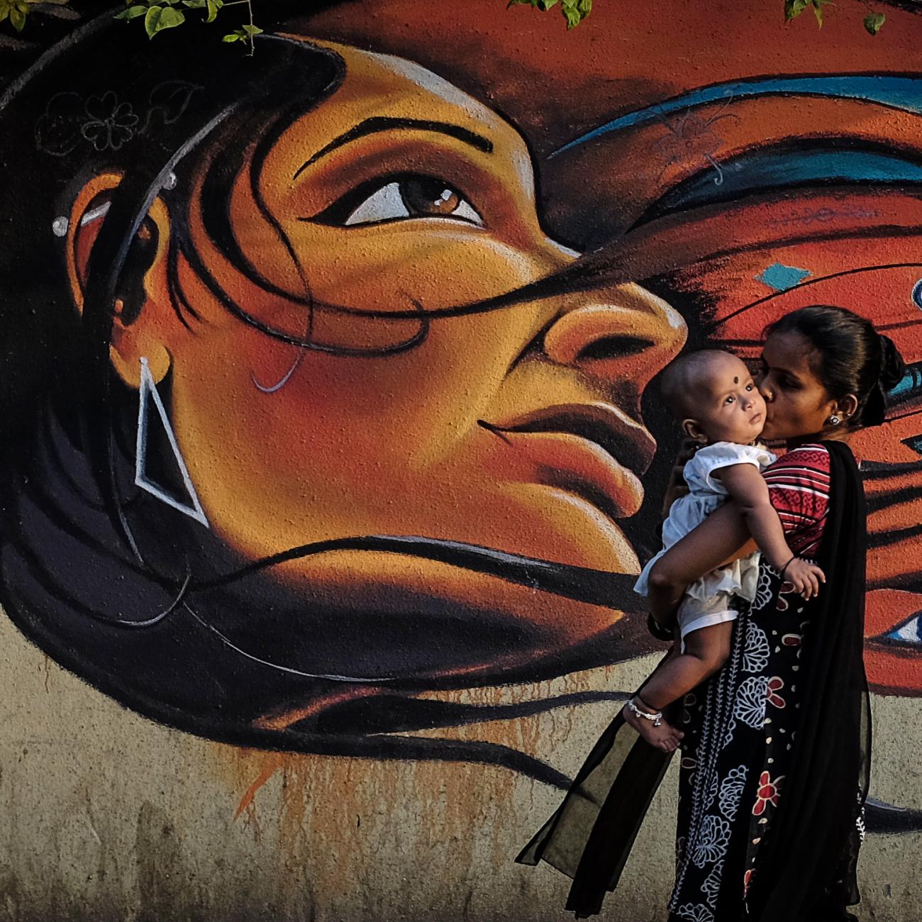 A mother kisses her child as she walks past graffiti in Mumbai March 27, 2014.