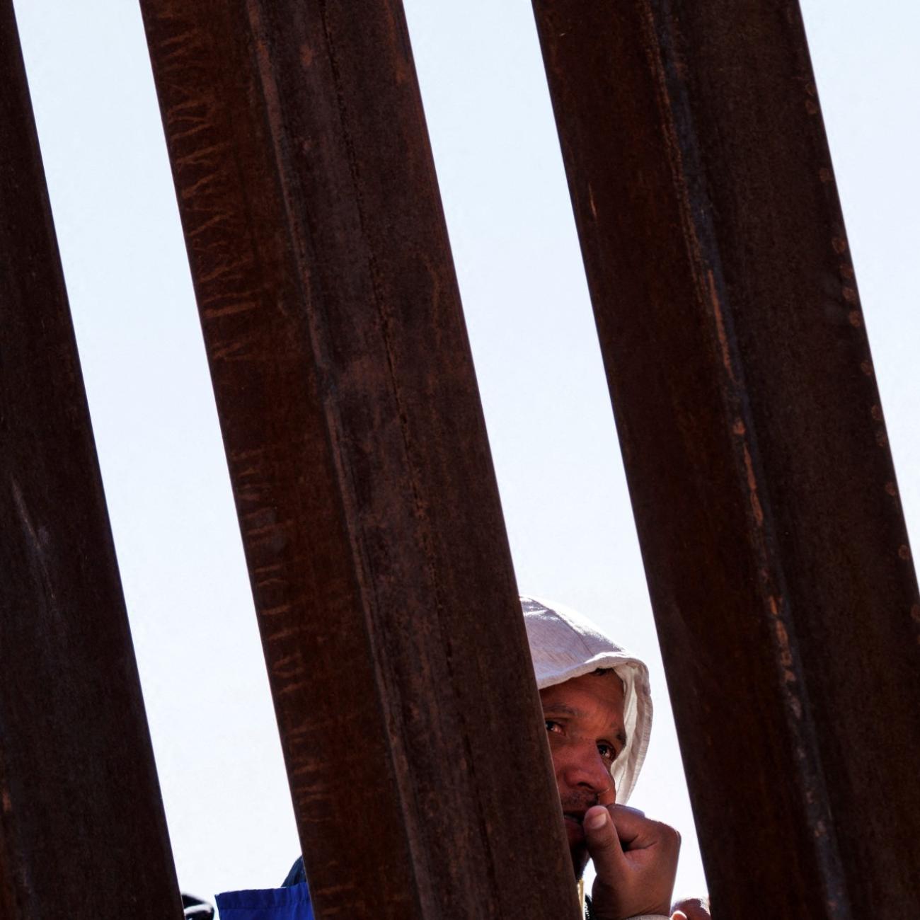 A migrant seeking asylum in the United States waits in line along the border fence at the Rio Bravo River, as seen from El Paso, Texas, on December 22, 2022.its in line along the border fence at the Rio Bravo river, the border between Mexico and the U.S., as seen from El Paso, Texas, on December 22, 2022.