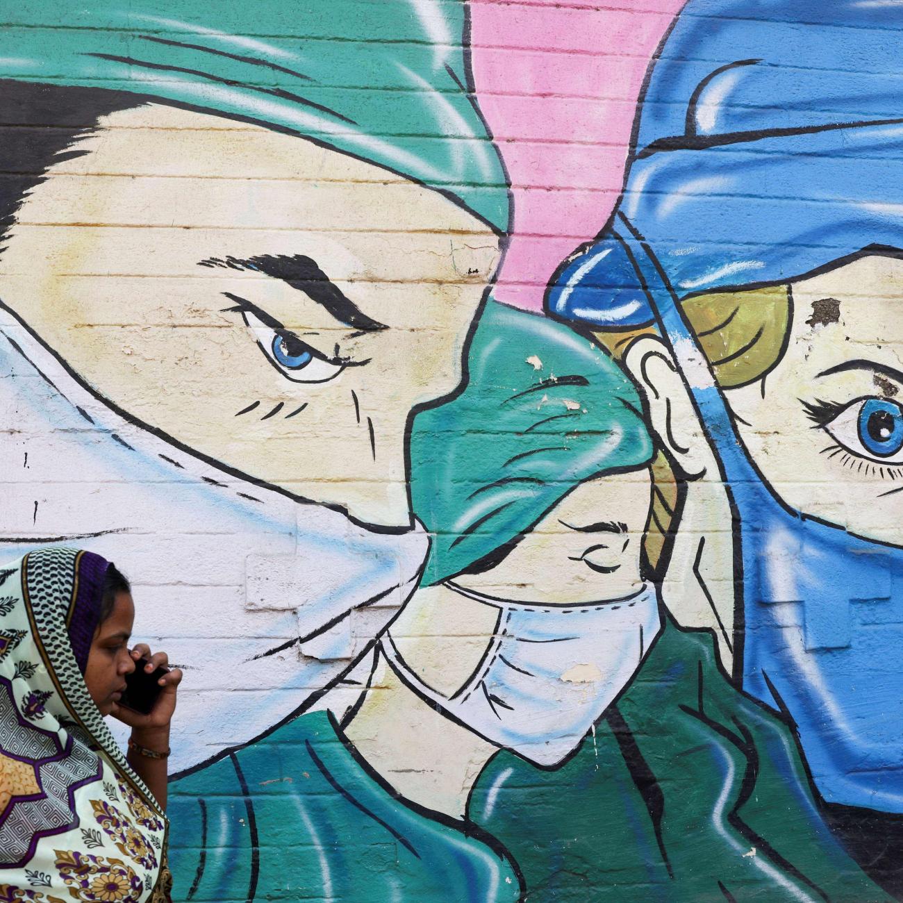 A woman walks past a coronavirus (COVID-19) themed mural on a street in Mumbai, India, March 28, 2023.