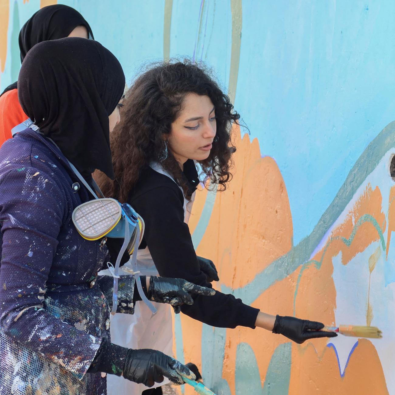 A volunteer paints a mural on a wall in Irbid, Jordan, February 25, 2023.