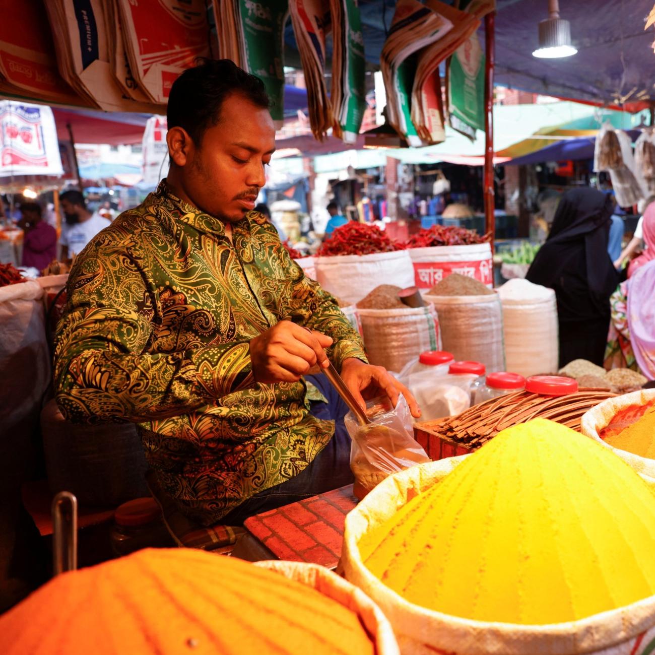 Man is seen in front of multiple piles of spices 