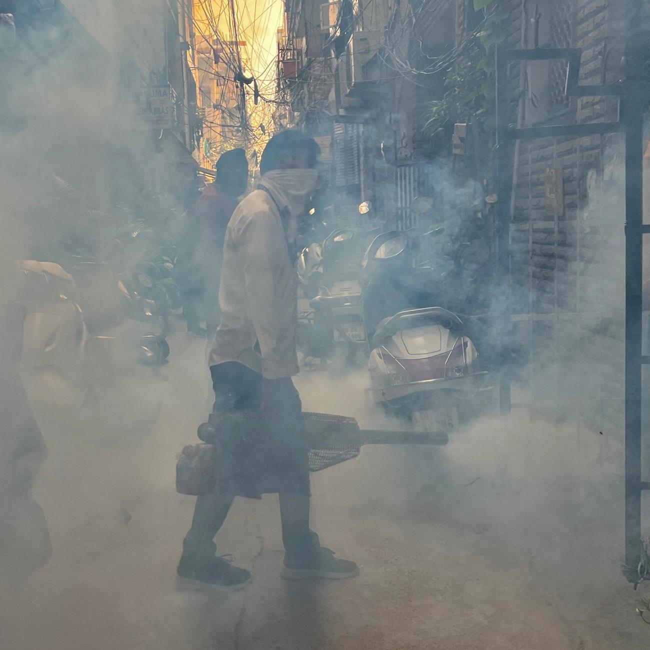 A health worker fumigates an alley in a residential neighbourhood