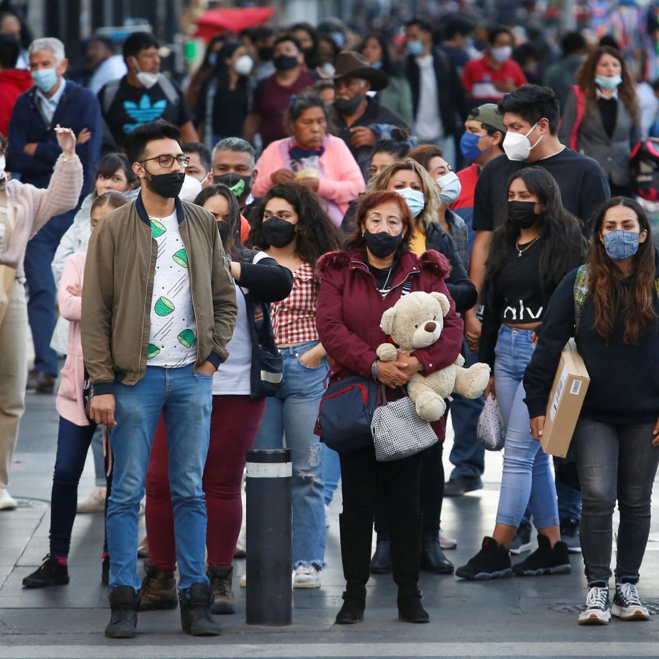 A crowd of people walk on a sidewalk.