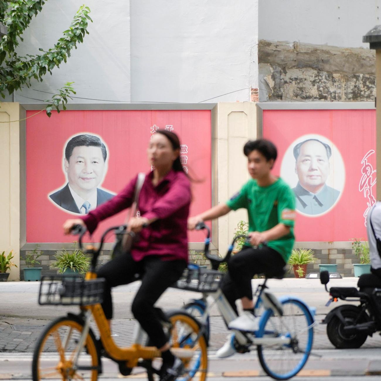 People pass by portraits of Chinese President Xi Jinping and late Chinese chairman Mao Zedong.