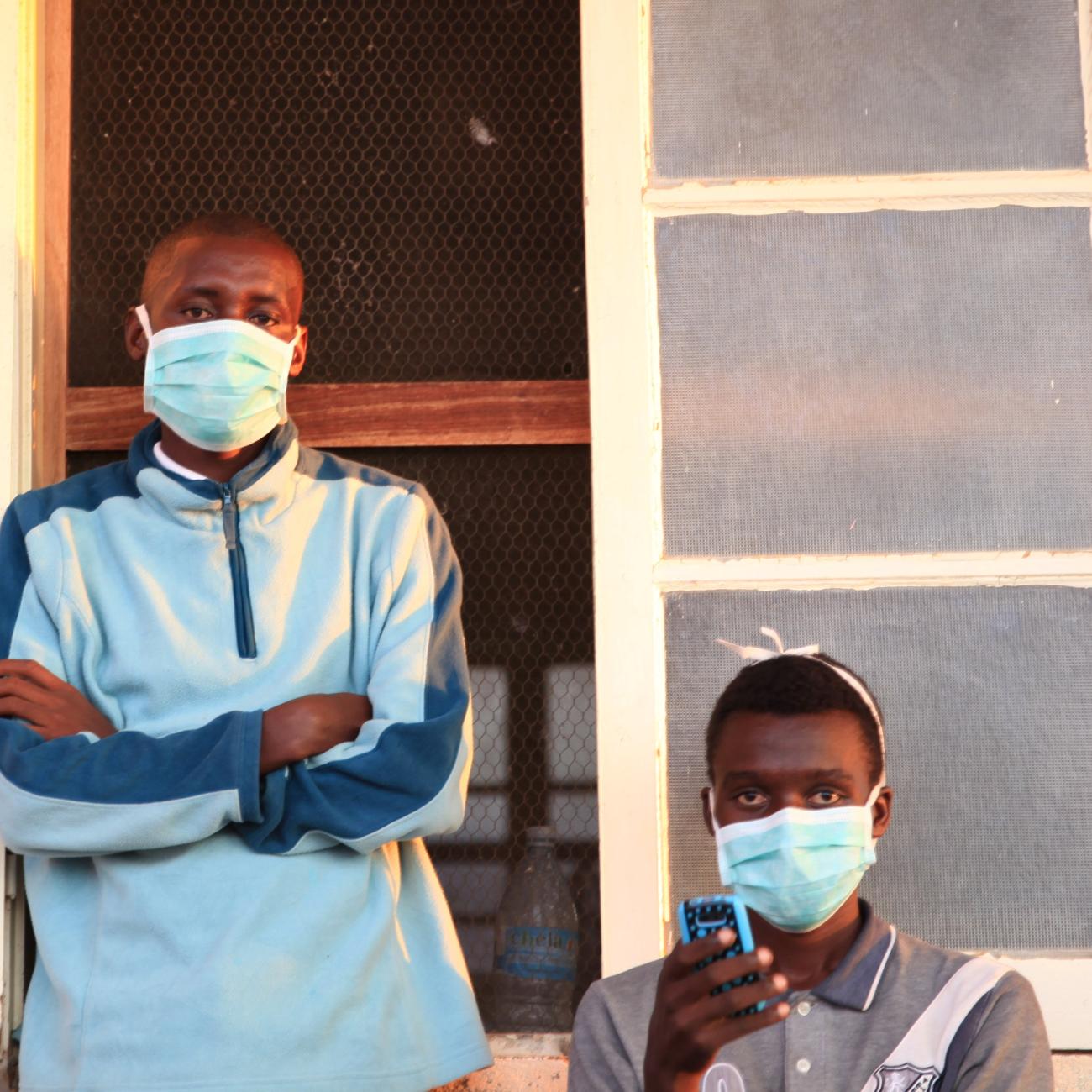 Tuberculosis patients, wearing masks to stop the spread of the disease, stand outside their ward at Chiulo Hospital.