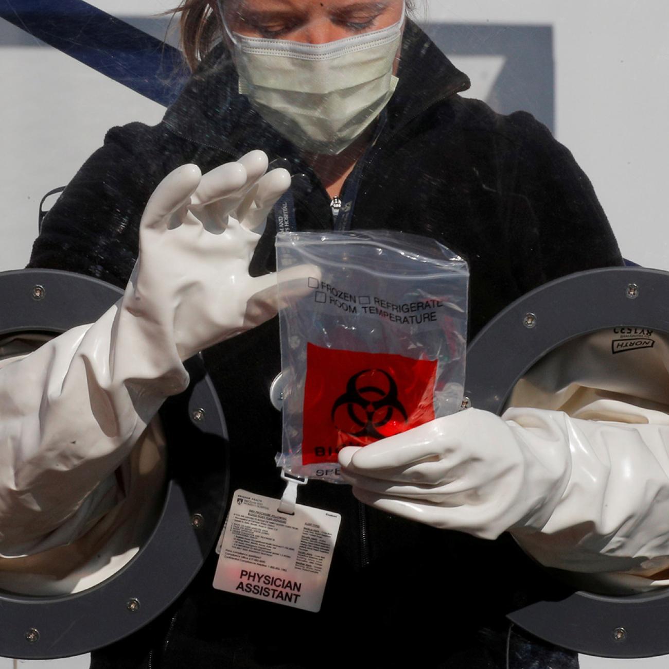 Physician Assistant Cori Kostick demonstrates a booth used to administer tests for coronavirus at the Brigham and Women Hospital in Boston, Massachusetts, on May 5, 2020. The photo shows the worker behind a protective barrier with incorporated gloves, allowing her to work with patients on the other side. REUTERS/Brian Snyder