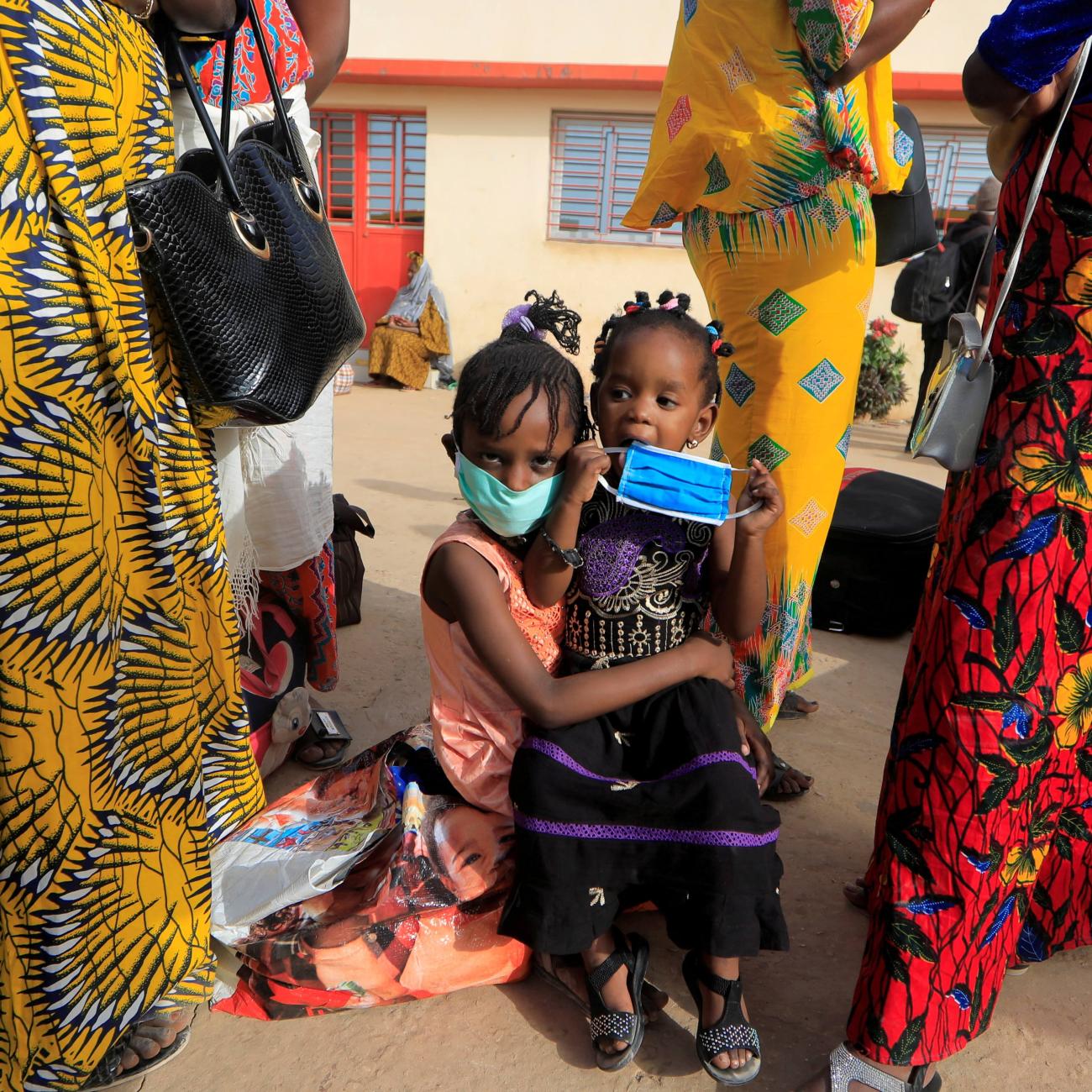 Teachers and their children wait to board a government chartered bus bringing people back to schools of countryside towns in Dakar, Senegal on May 28, 2020.