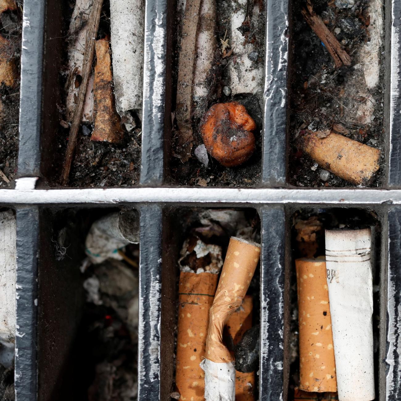 Discarded cigarette butts are seen lodged in a sidewalk grating in Manhattan.