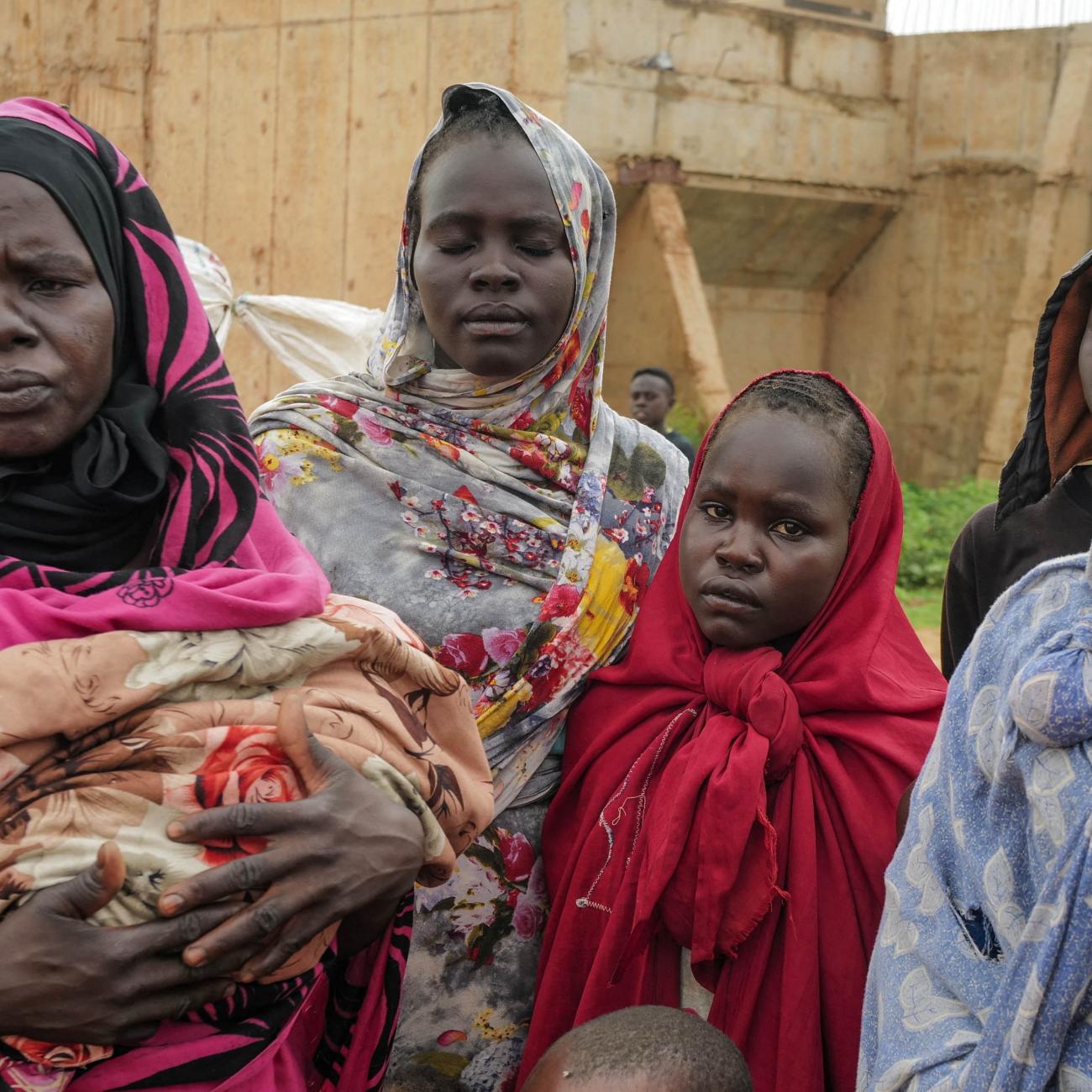 Sudanese women, who fled the conflict in Murnei in Sudan's Darfur region, look on while crossing the border between Sudan and Chad.