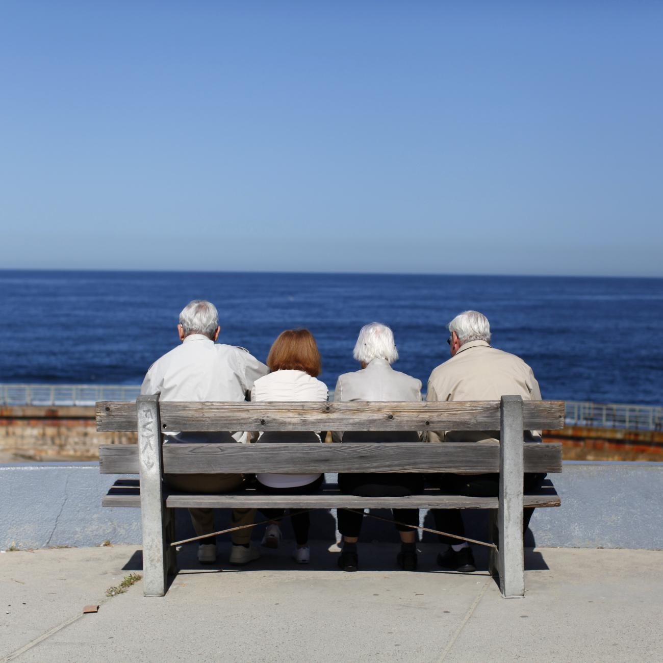 A pair of elderly couples view the ocean and waves along the beach.