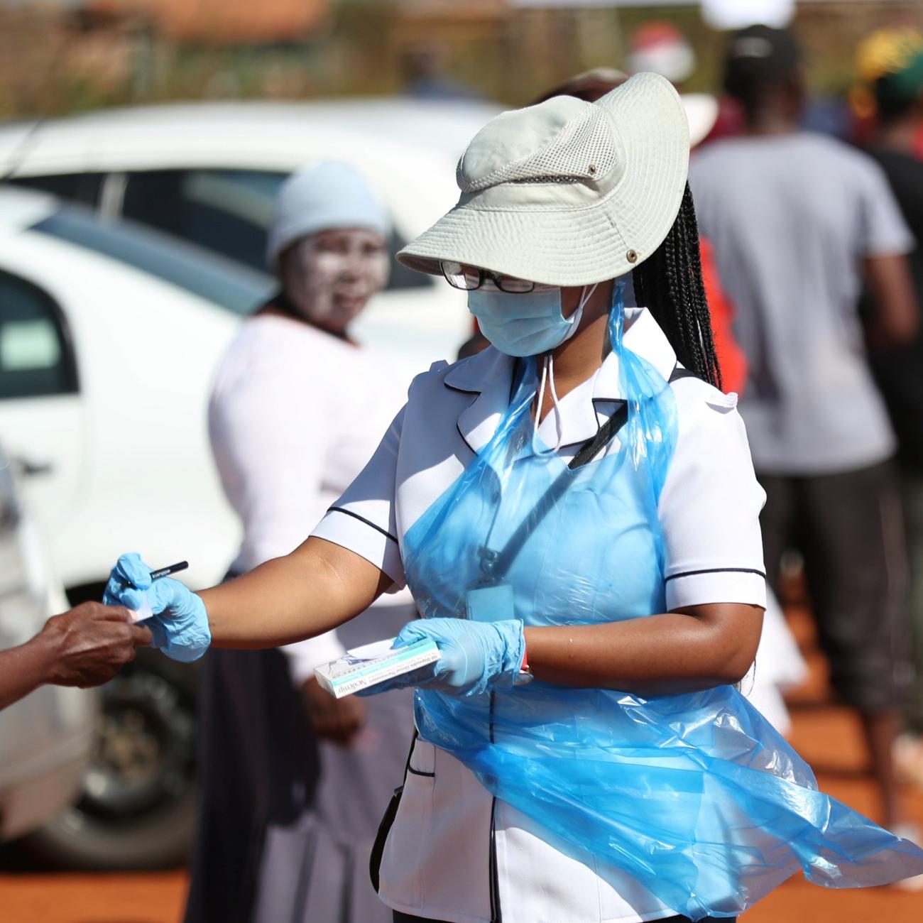 A member of medical staff attends to residents as they queue during screening and testing campaign aimed to combat the spread of COVID-19, in Lenasia, South Africa, on April 21, 2020.