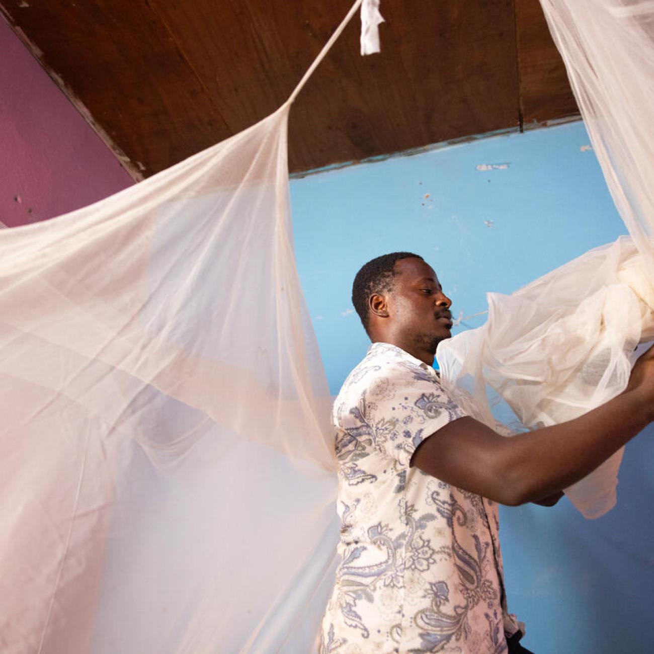 Tomnjong, a father of two, assembles a dual AI insecticide-treated mosquito net in his home.