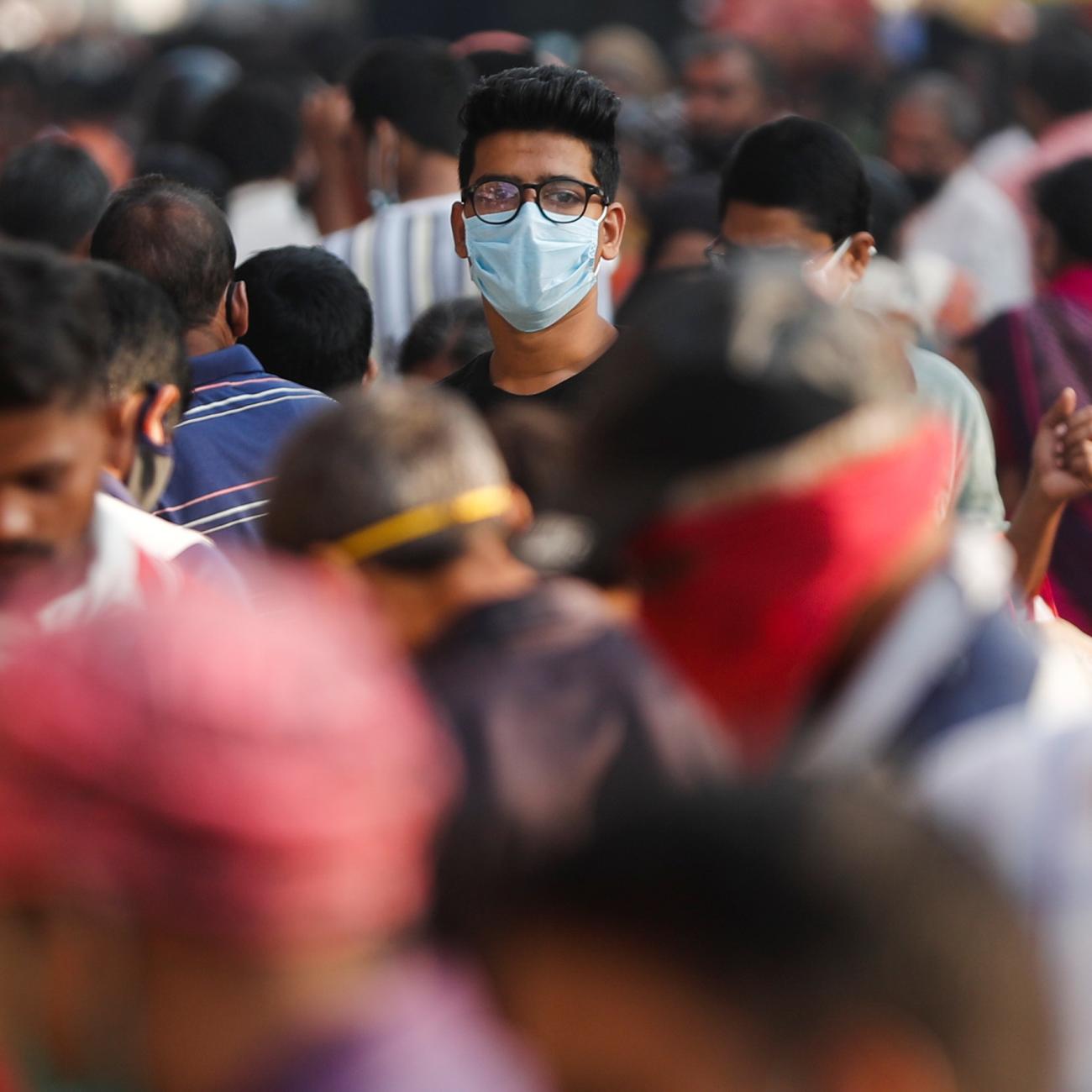 A man wearing a protective mask is seen among people at a crowded market amid the spread of COVID-19.
