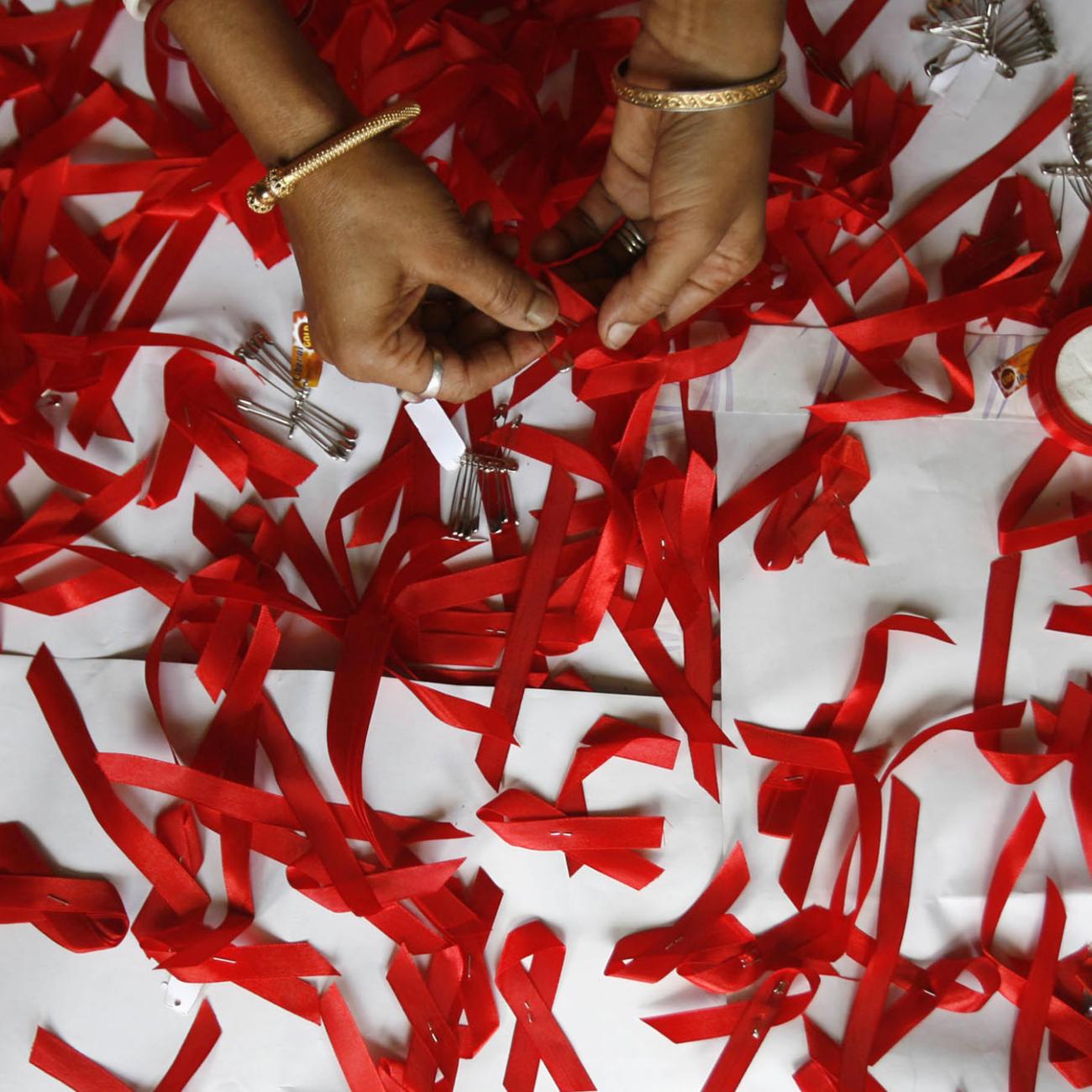 A volunteer suffering from HIV/AIDS makes AIDS symbols with red ribbons during a vaccination program.