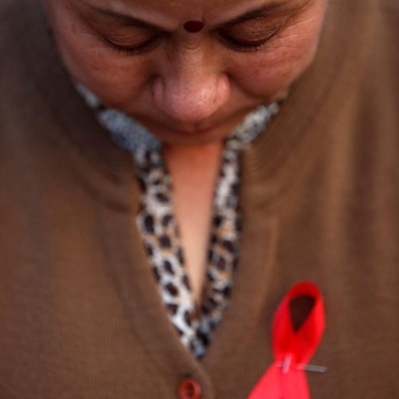 A participant with a red ribbon pin observes a minute of silence during a HIV/AIDS awareness campaign.