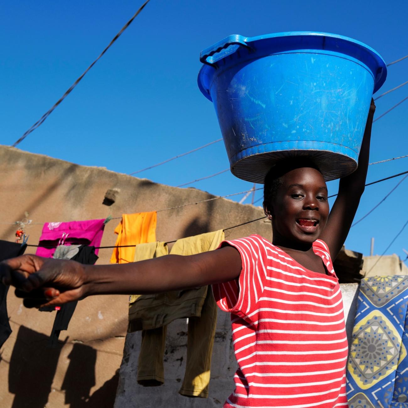 A girl carries a bucket with laundry on her head while heading home as the spread of the coronavirus disease continues, in Yoff neighbourhood, Dakar, Senegal on January 26, 2021.