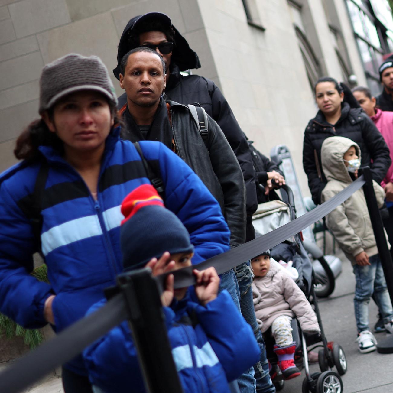 Recently arrived migrant families and others stand in line for a free meal provided by a Lutheran Church.