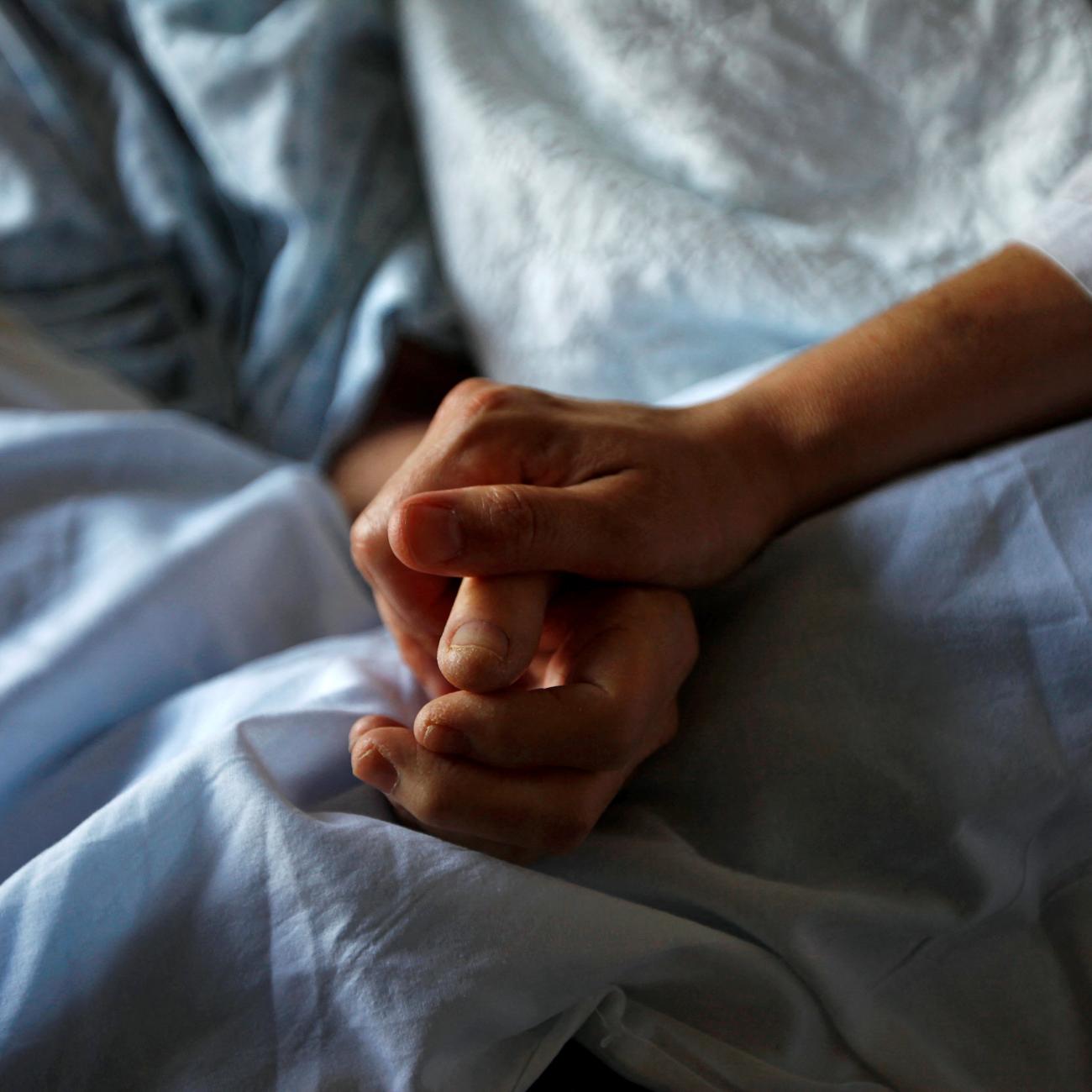 A woman holds the hand of her mother who is dying from cancer during her final hours, at a palliative care hospital, in Winnipeg, Canada, onJuly 24, 2010.